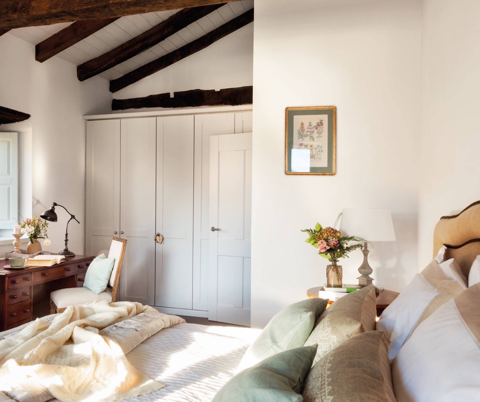 Dormitorio de casa rústica con paredes blanca y vigas de madera