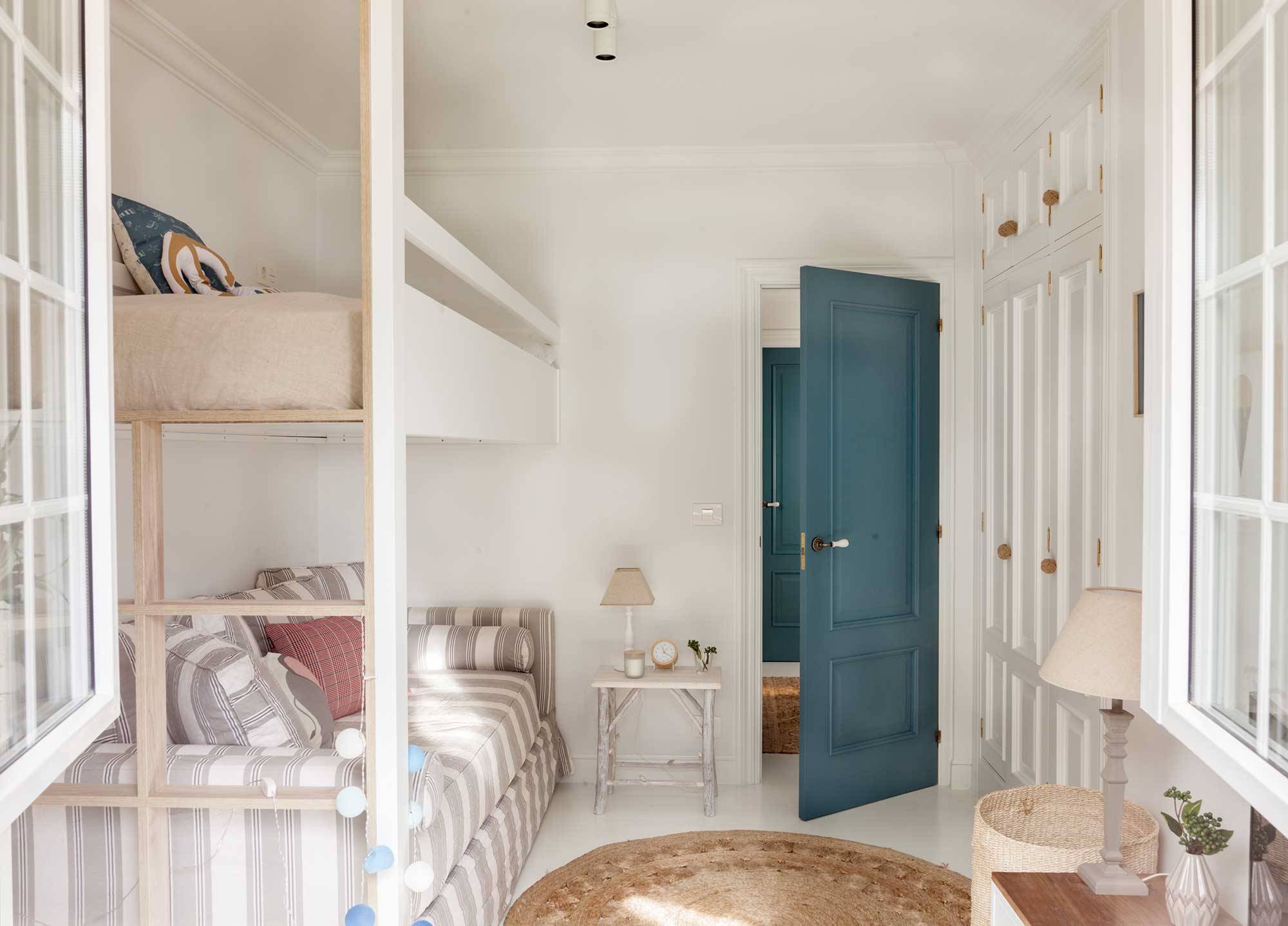 Dormitorio infantil con armarios en blanco y puerta azul
