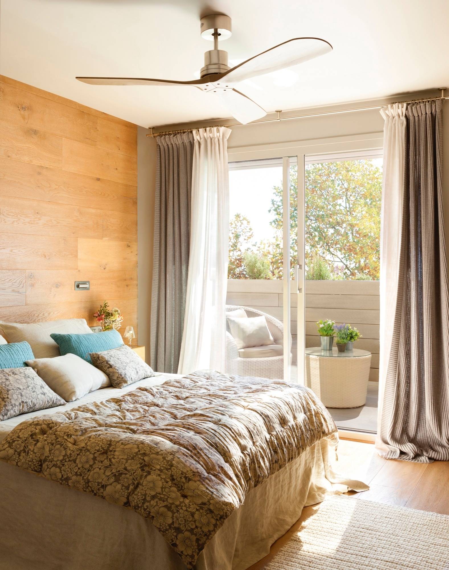 Dormitorio con pared revestida de madera y terraza. 