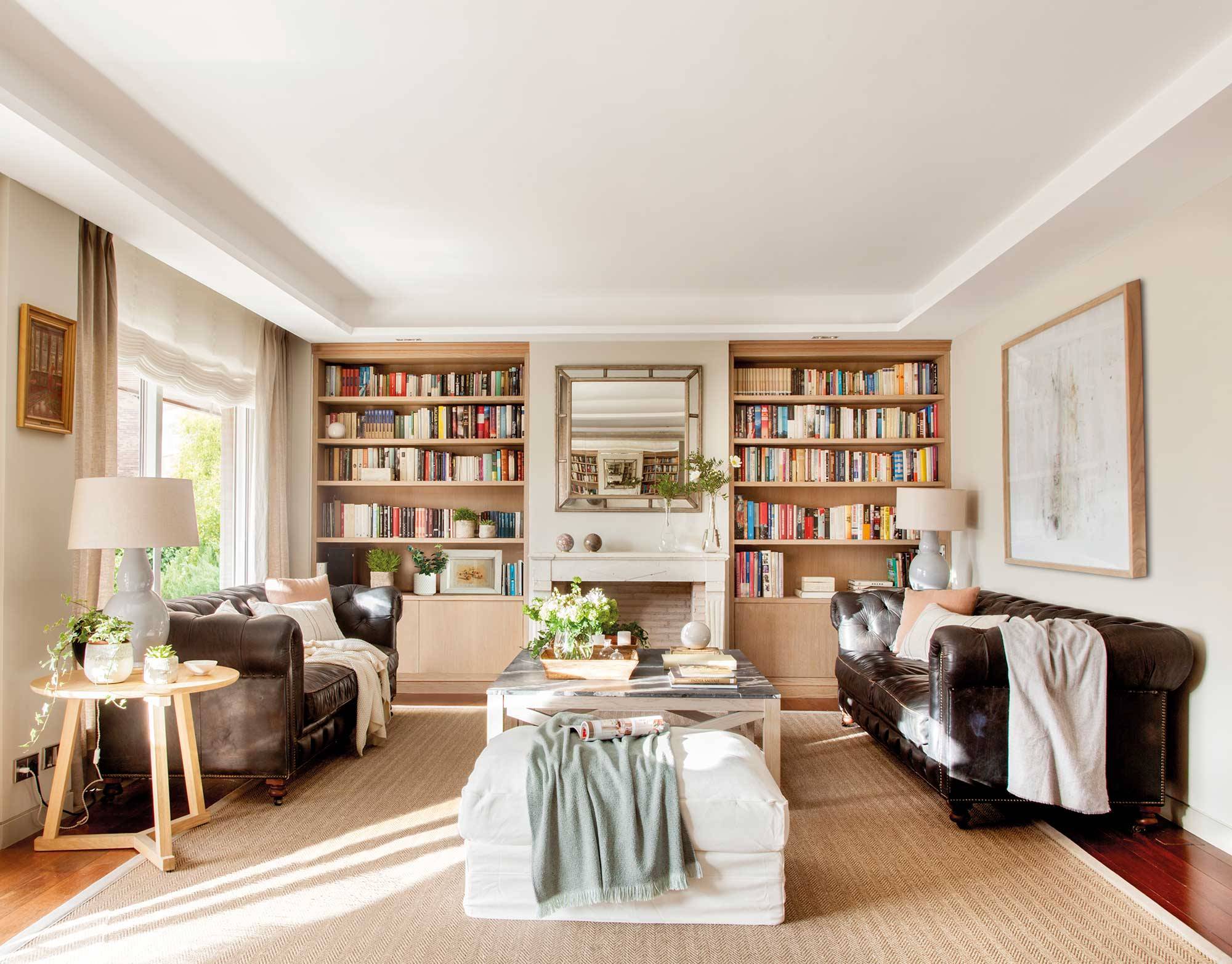 Salón con chimenea, sofás chéster enfrentados y dos librerías simétricas.