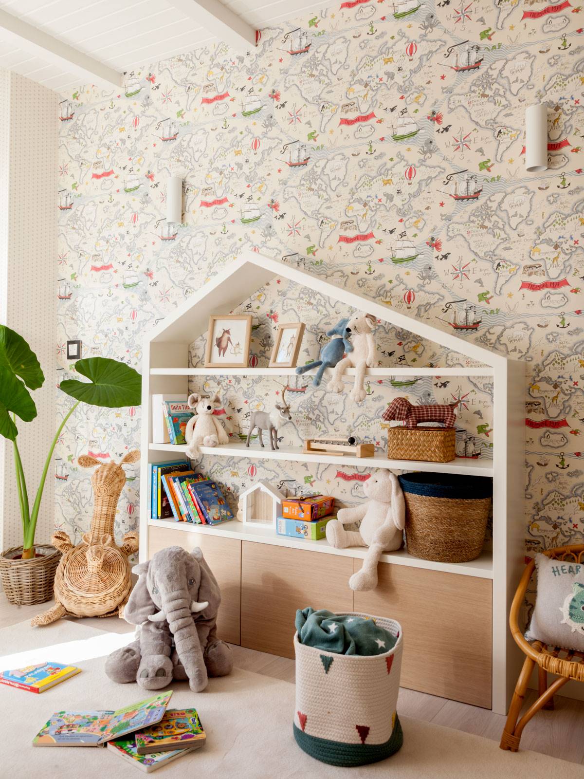 Zona de juegos con papel pintado, mueble con forma de casa, juguetes y alfombra.