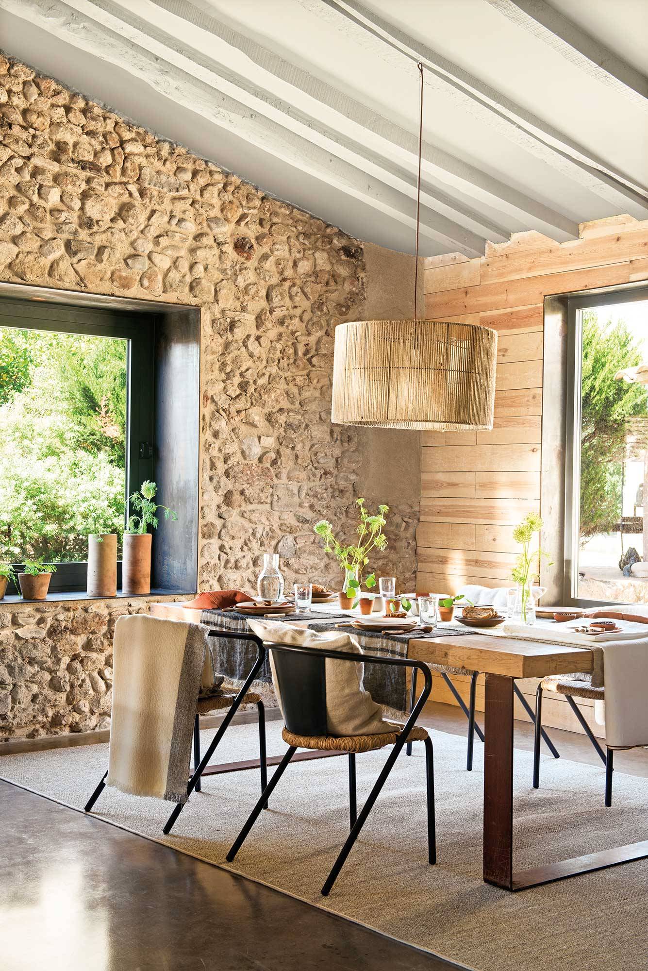 Comedor con paredes de piedra y mesa y sillas modernas. 