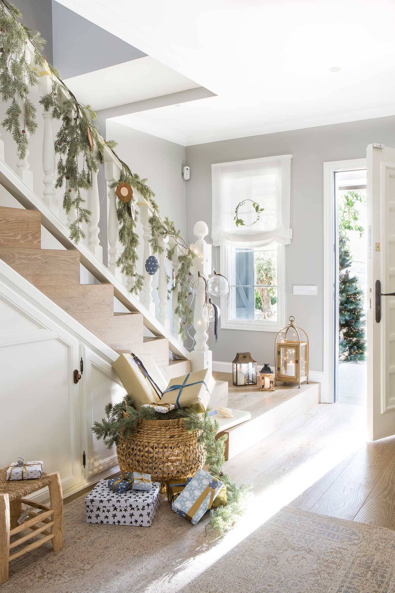Recibidor de casa con escalera con barandilla blanca y guirnalda de verdes y adornos_00515342 O