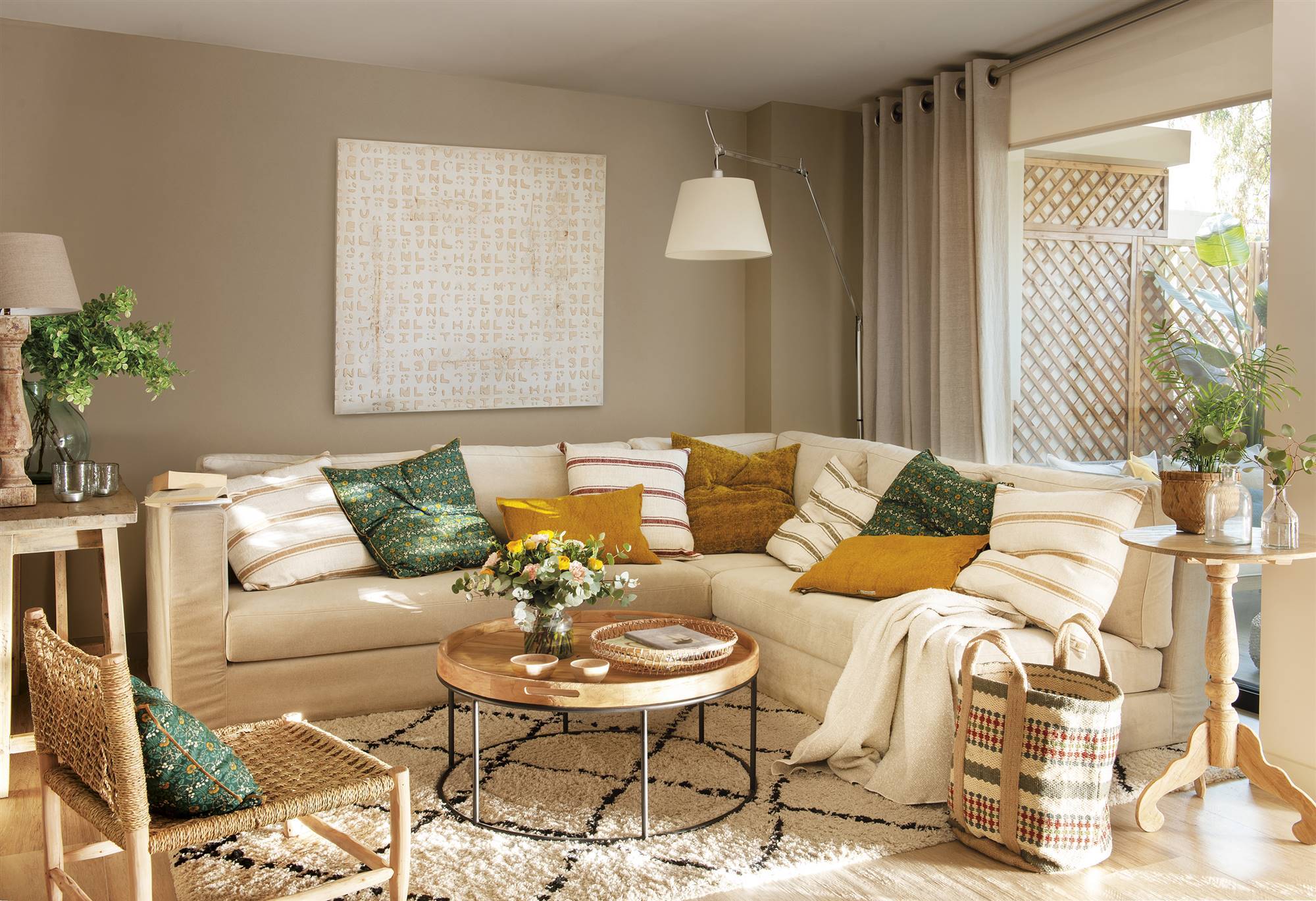 Salón pequeño con paredes beige y sofá rinconero de color blanco. 