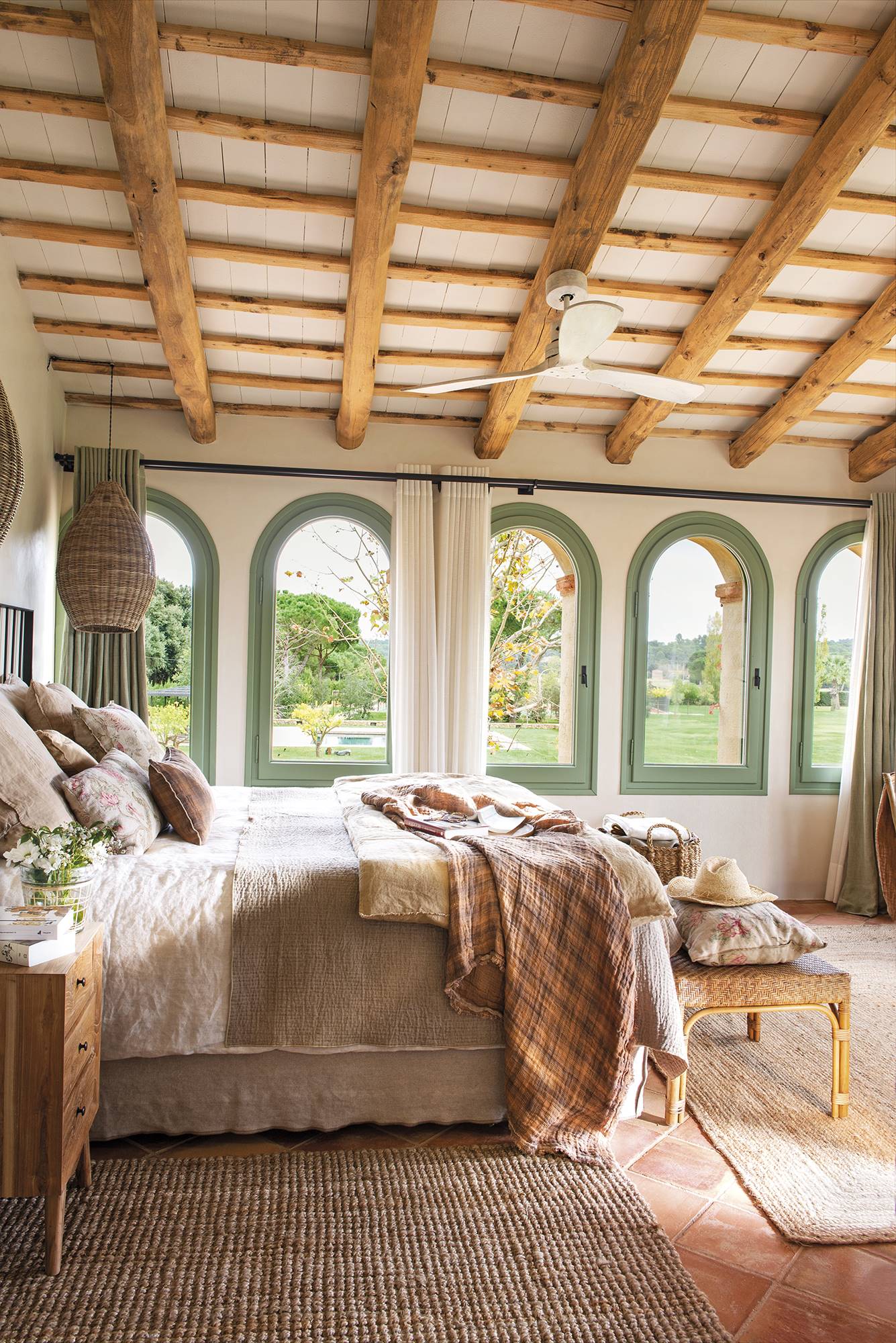 Dormitorio de estilo rústico con cama, vigas en el techo, ventanas verdes.