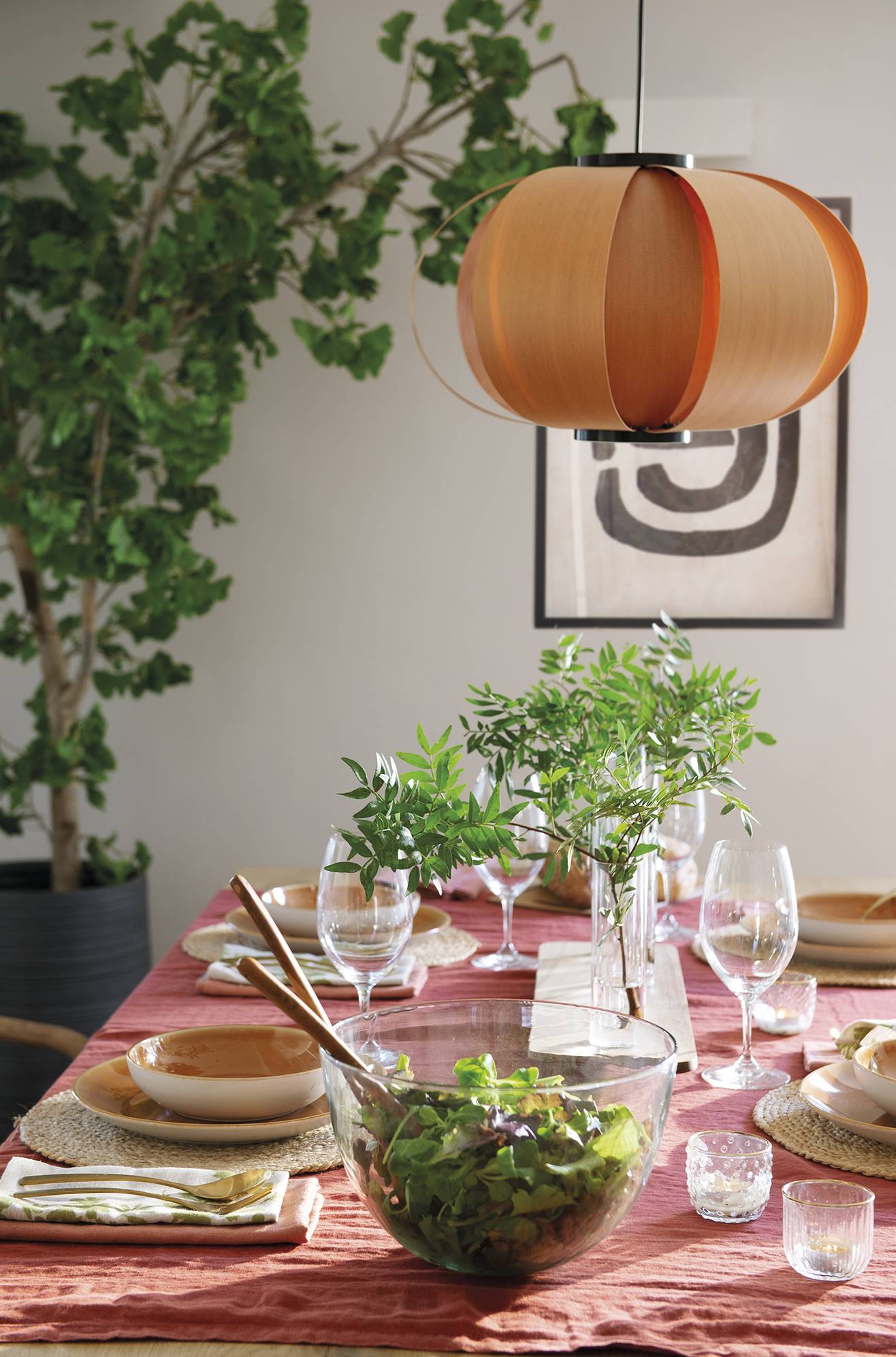 Mesa con mantel rosa y lámpara de madera. 