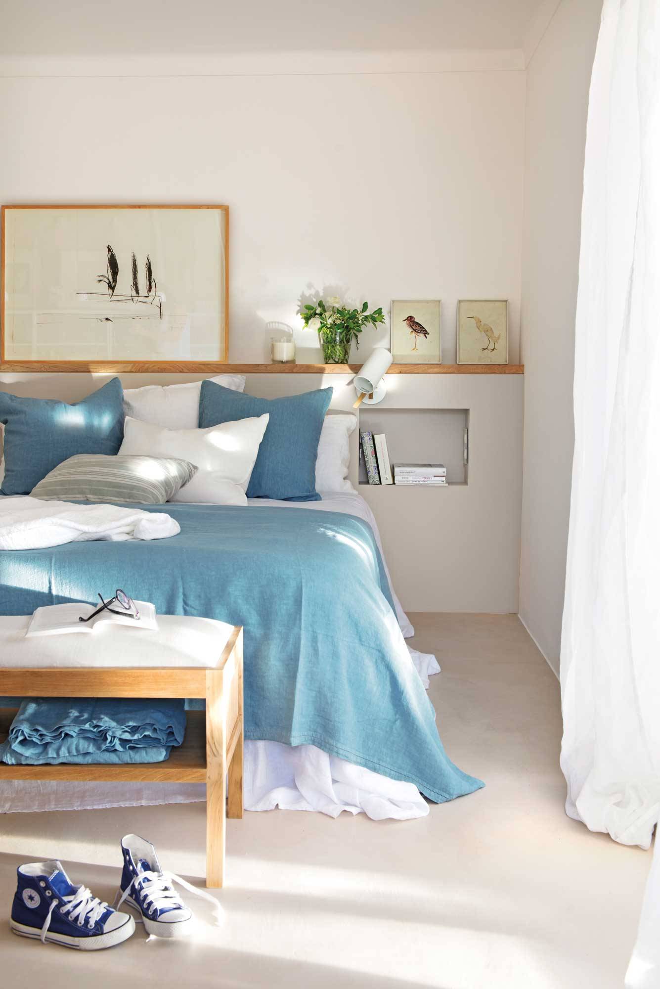 Dormitorio con cabecero de obra y ropa de cama azul y blanca. 