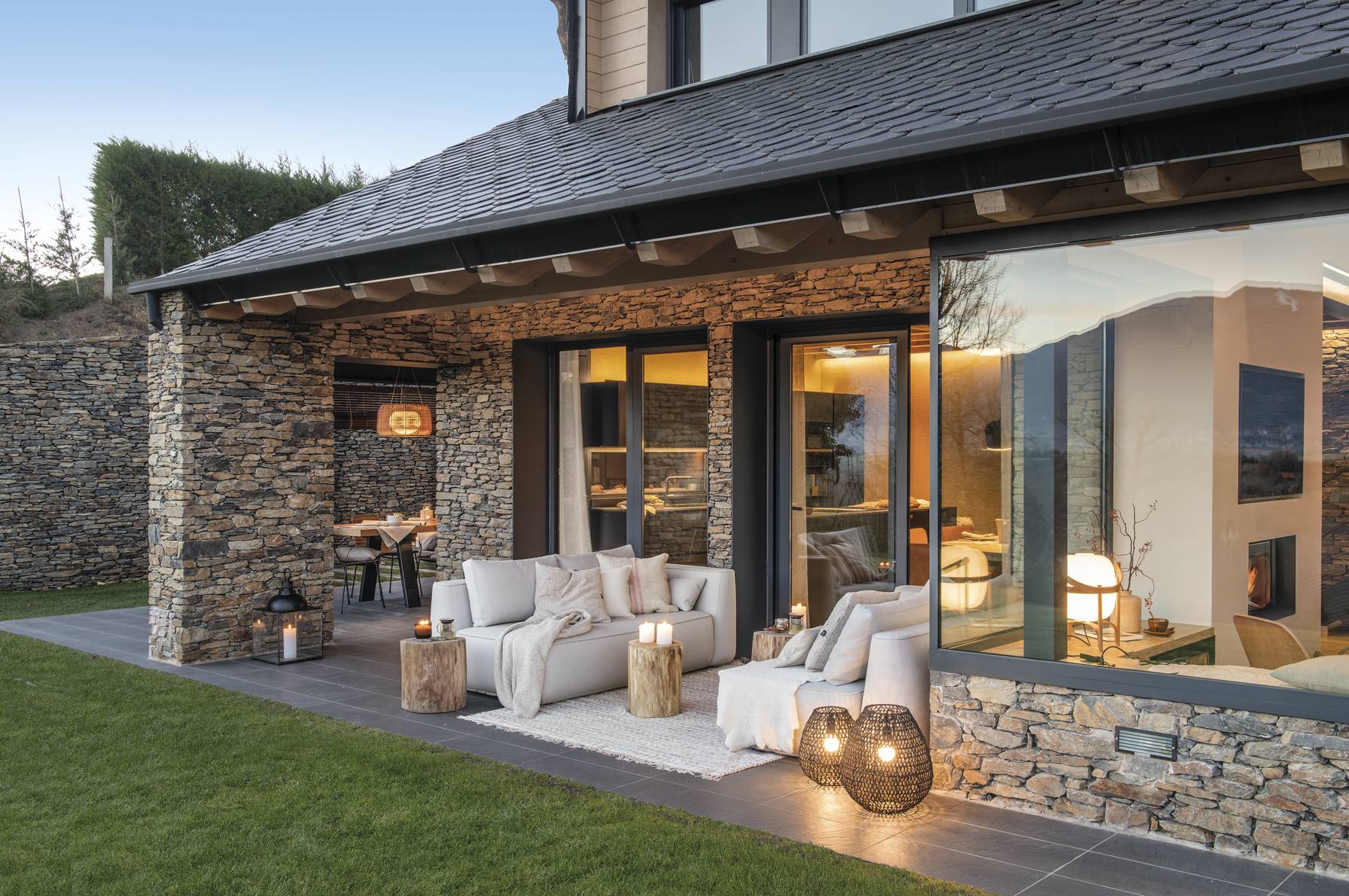 Fachada de casa rústica de piedra con porche iluminado.