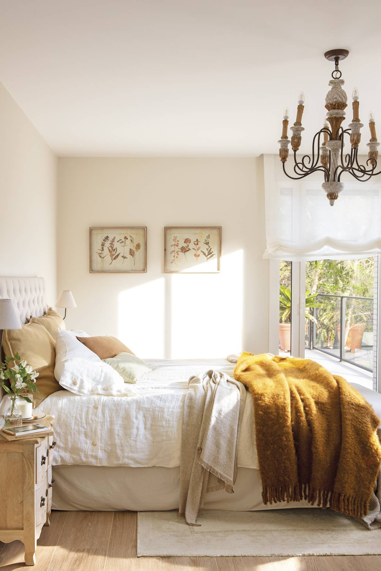 Dormitorio elegante con lámpara de chandelier y cabecero de capitoné.