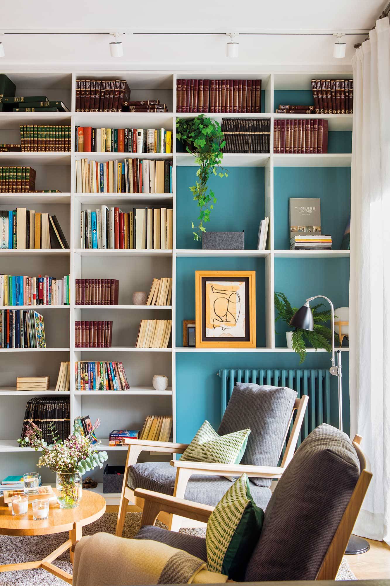 Salón con librería metálica blanca hasta el techo con trasera azul.