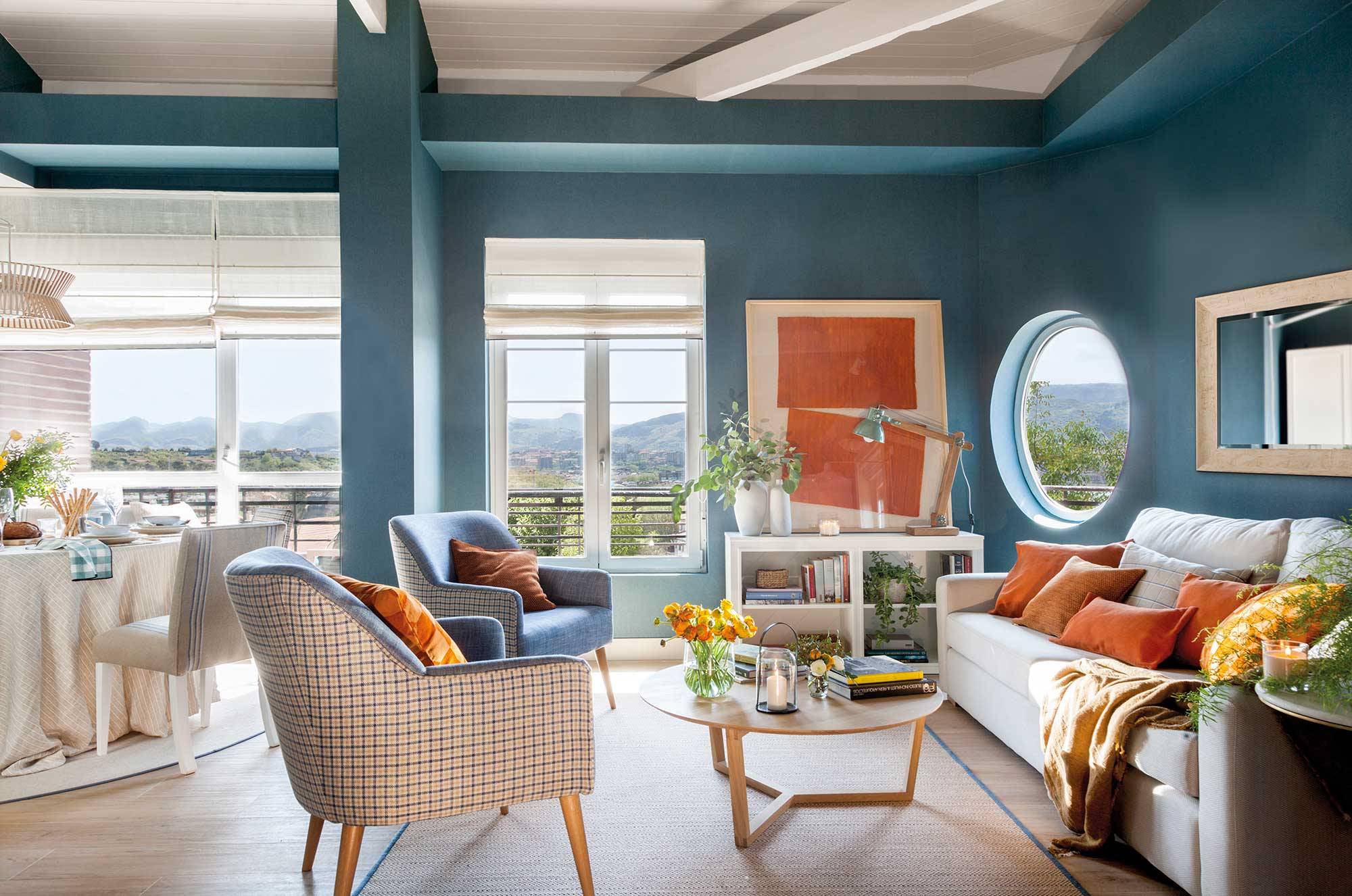 Salón con paredes azules y cuadro naranja.