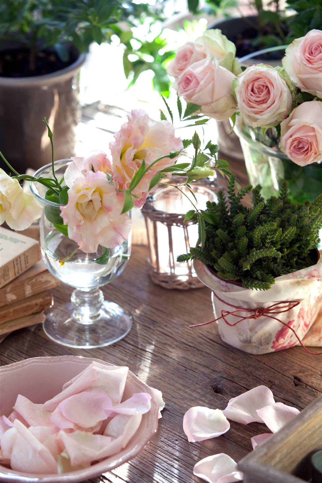 Mesa decorada de San Valentín con jarrón con flores y pétalos de rosa.