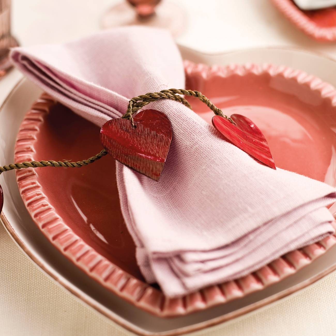 Servilleta rosa con servilletero de corazones y vajilla con forma de corazo´n en rojo y rosa.