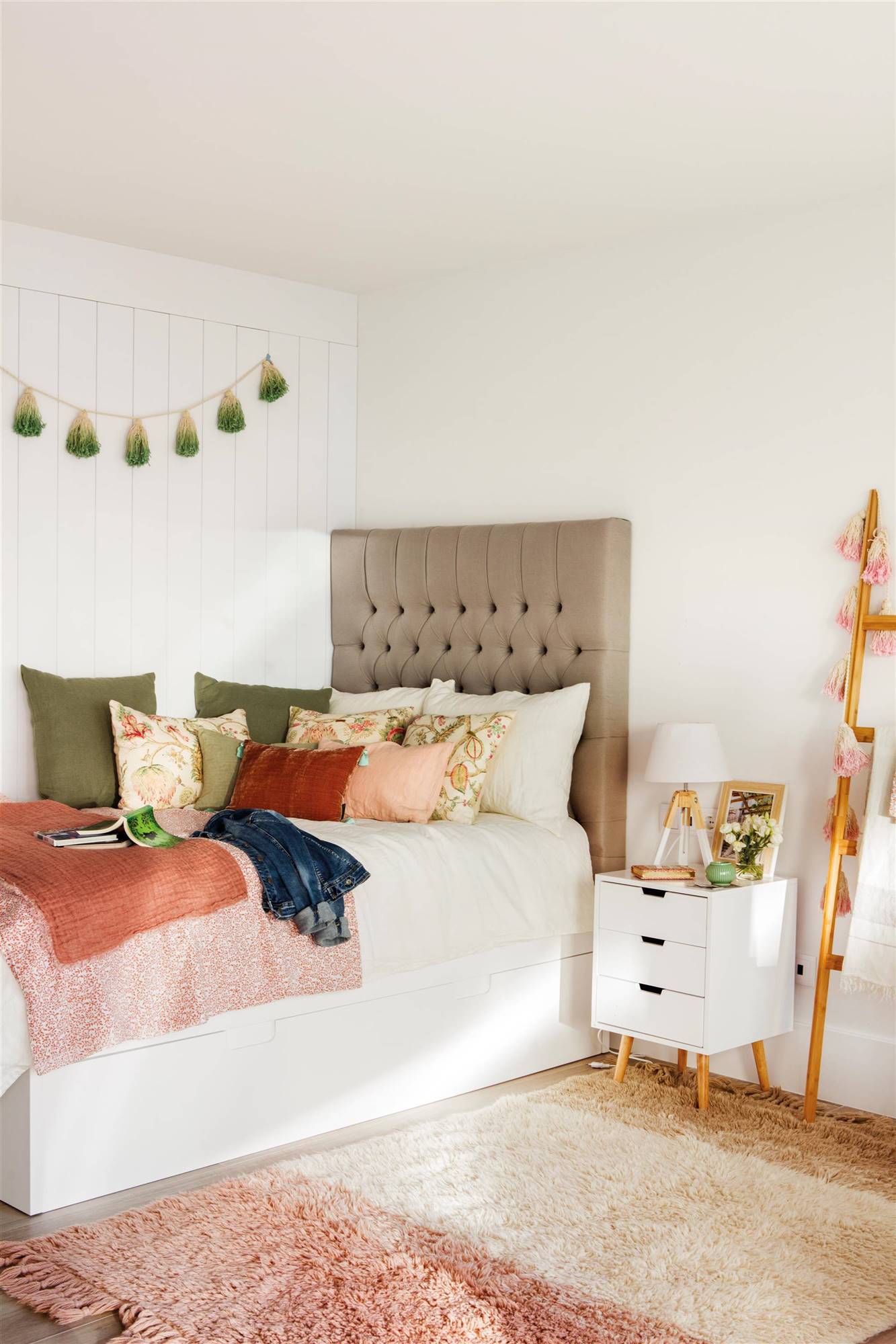 Dormitorio infantil con alfombra, cama nido, cabecero de capitoné y cojines.