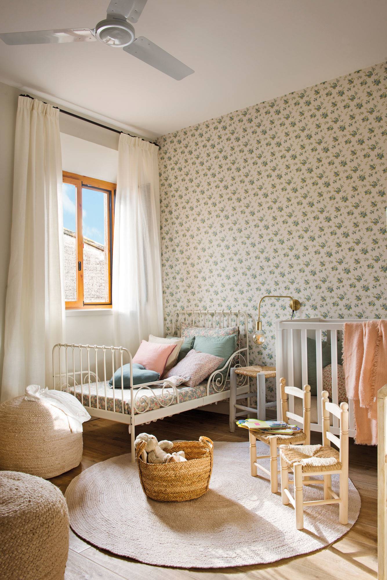 Habitacio´n infantil cama y cuna y papel pintado. Pufs, sillas y alfombra de fibra vegetal. 