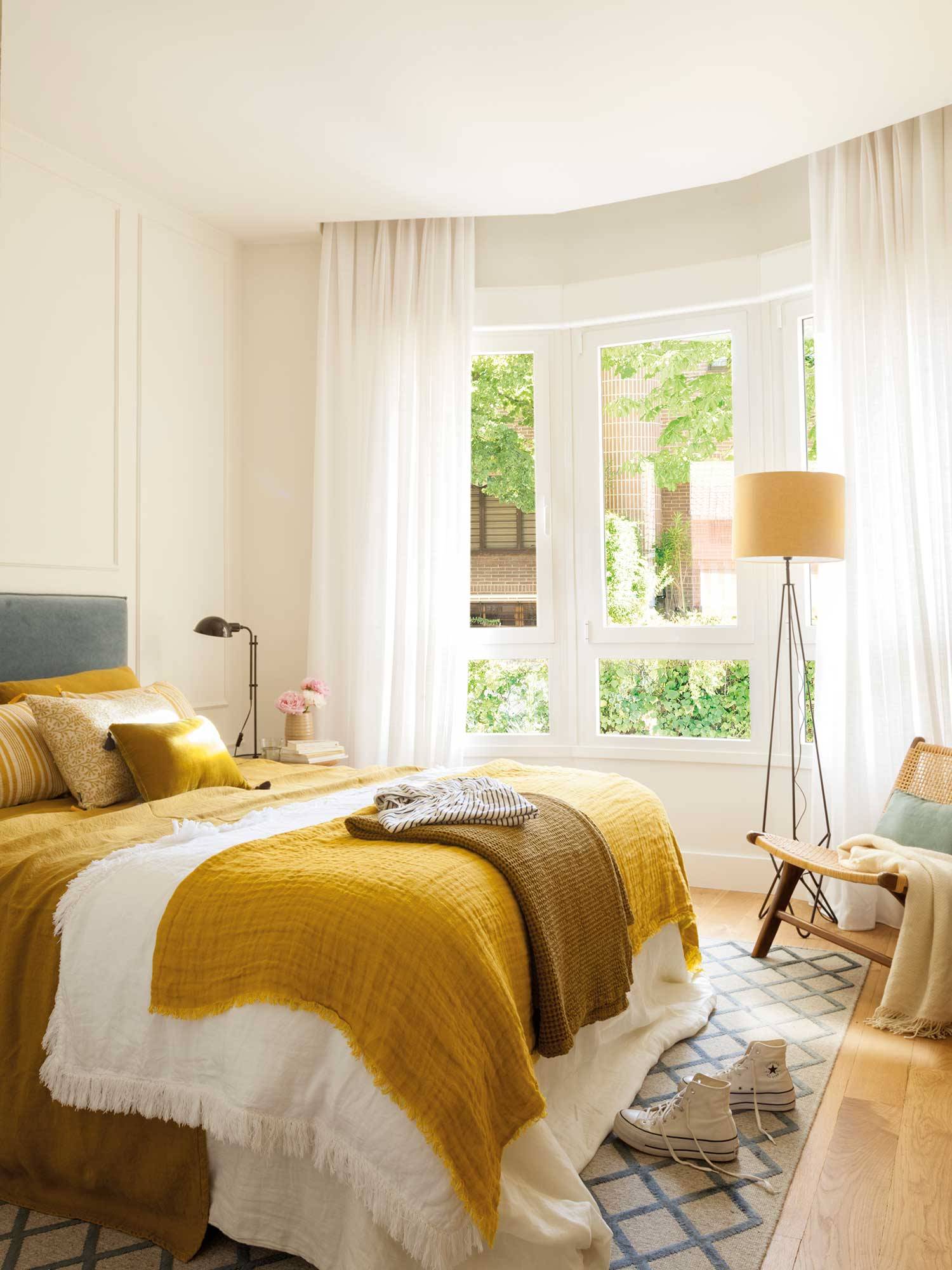 Dormitorio blanco con molduras y ropa de cama amarilla y butaca 0528735