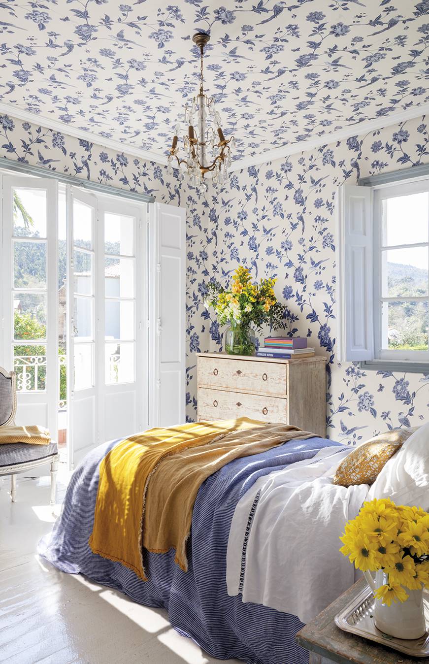 Dormitorio con papel pintado de flores azules con fondo blanco. 