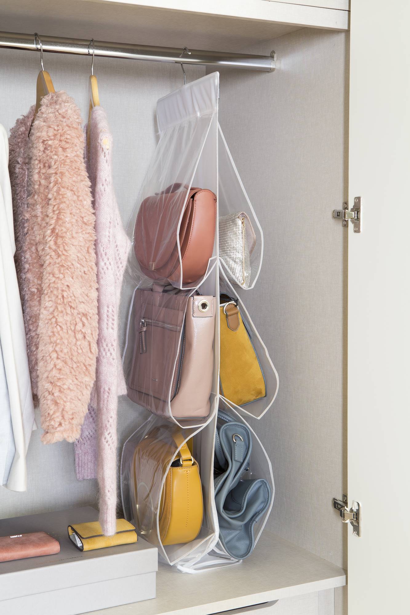 Interior de un armario con colgador de bolsos de plástico.