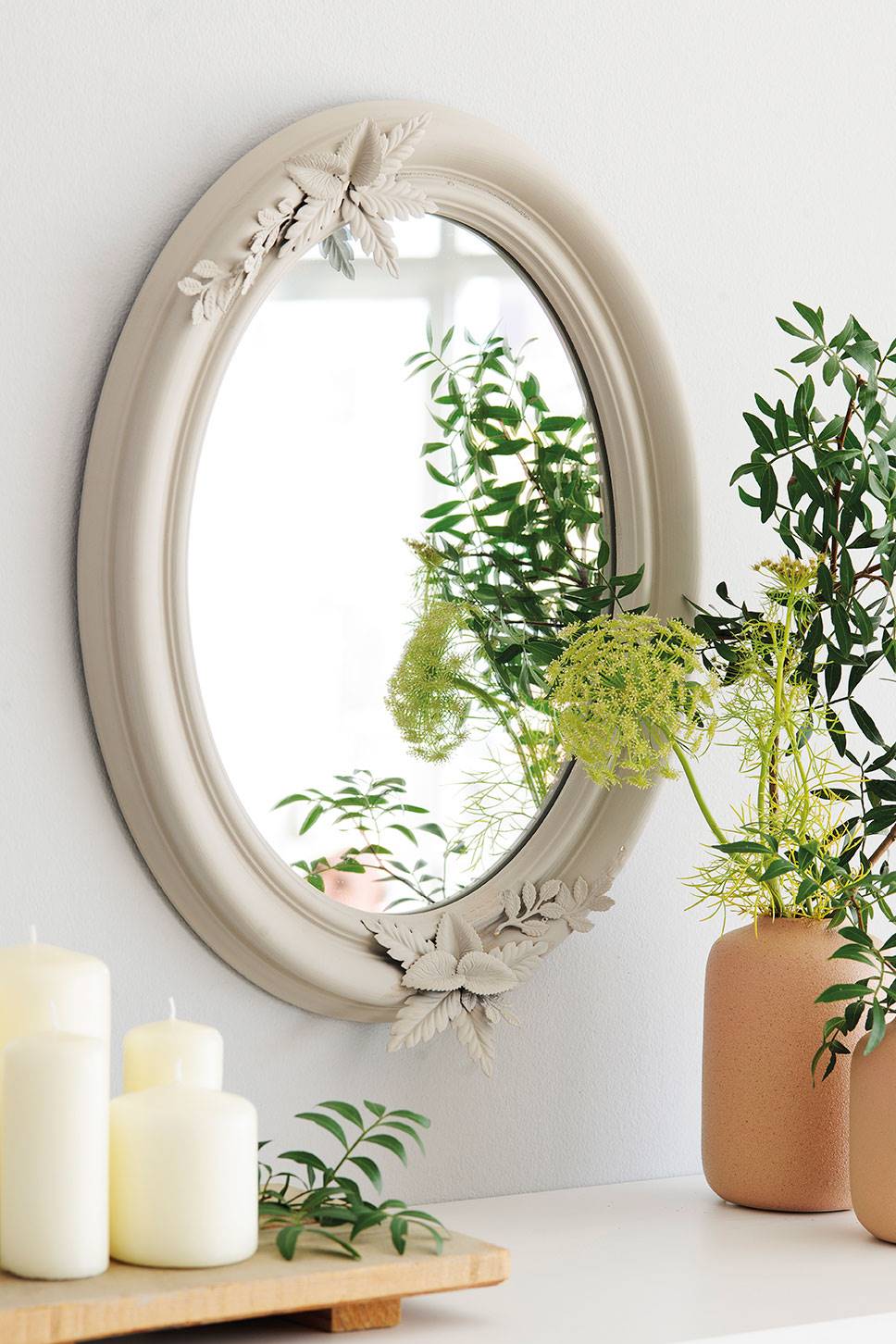 Detalle decorativo con velas, jarrones y un espejo de estilo romántico con marco blanco 00462283