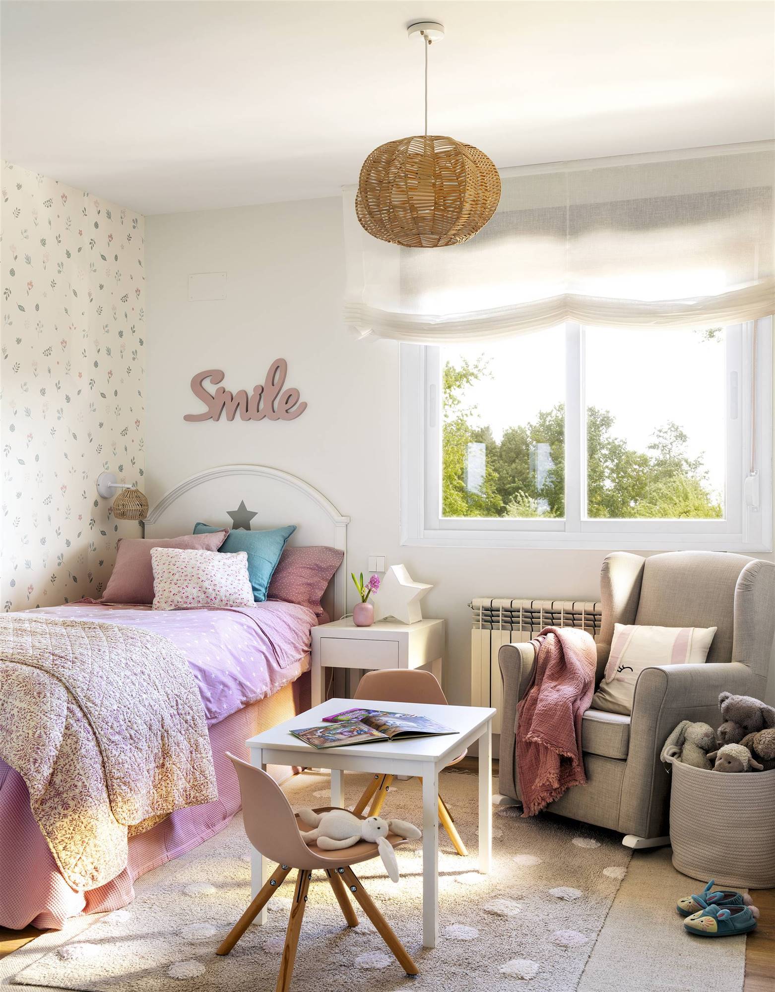 Dormitorio infantil con papel pintado, butaca y ropa de cama rosa.