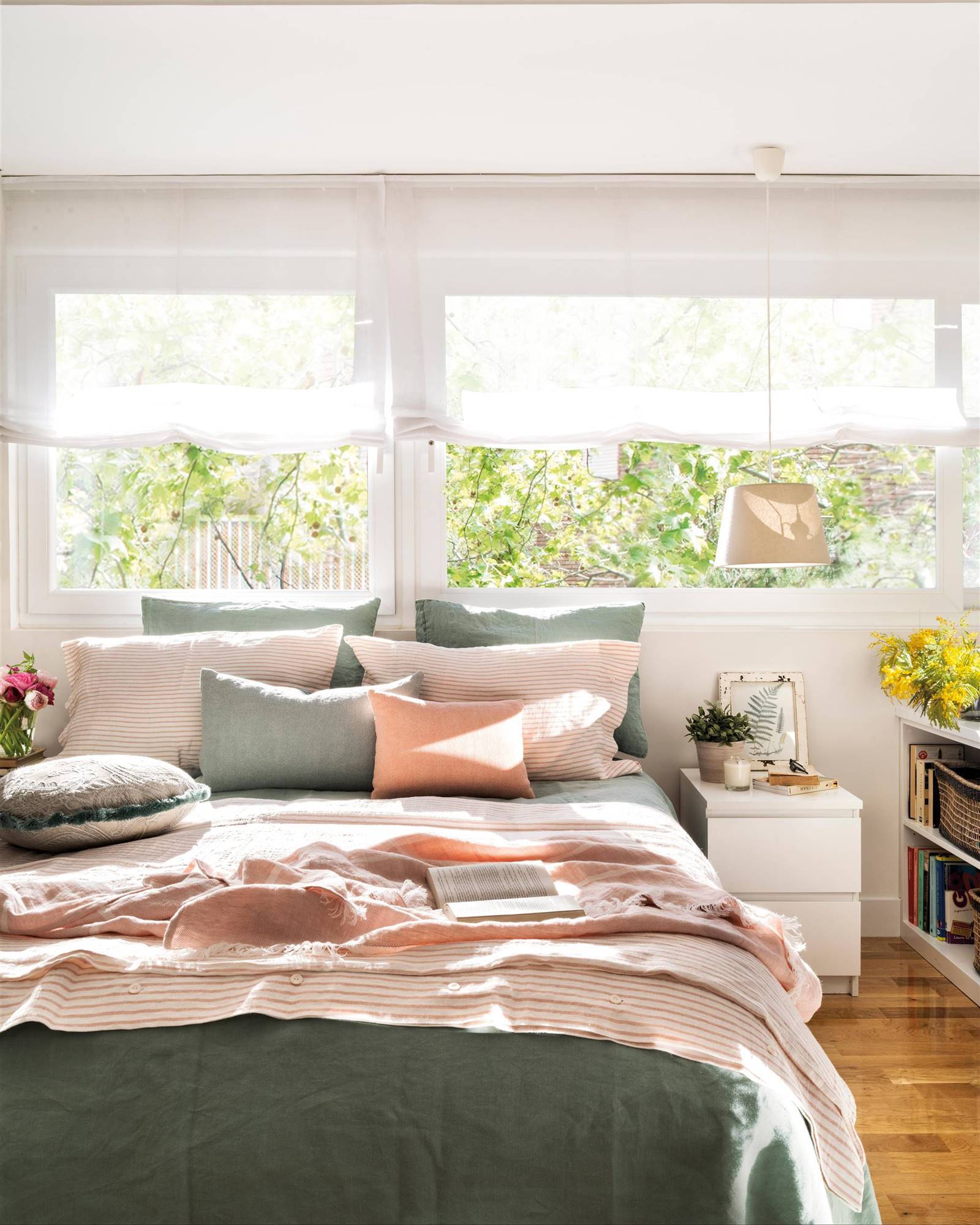 Dormitorio de primavera con la cama bajo la ventana y ropa en verde y salmón.