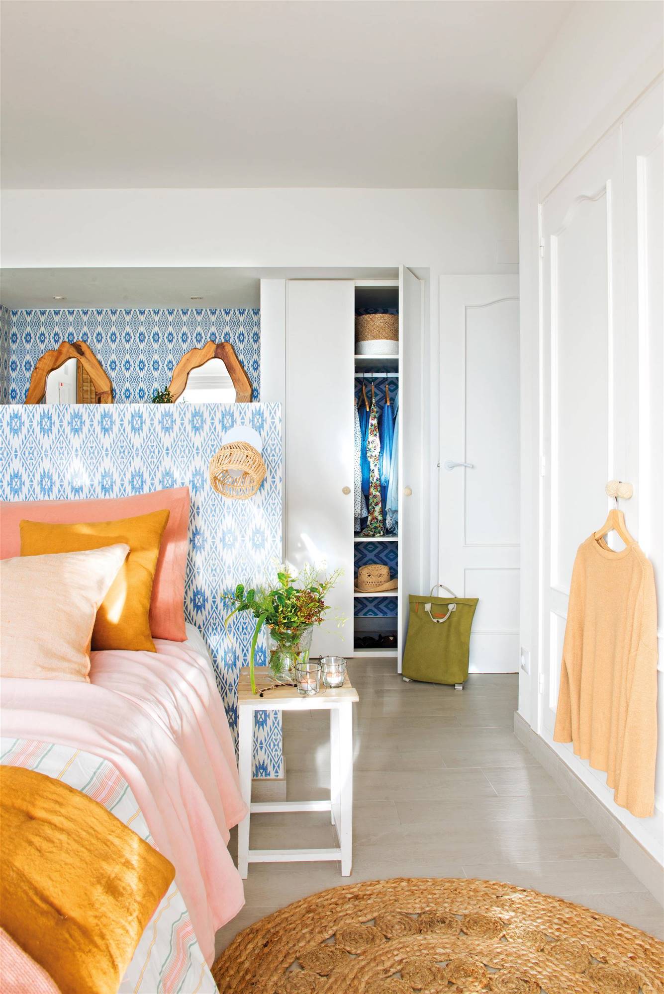 Dormitorio de primavera con cabecero empapelado con motivos geométricos en azul y baño detrás.