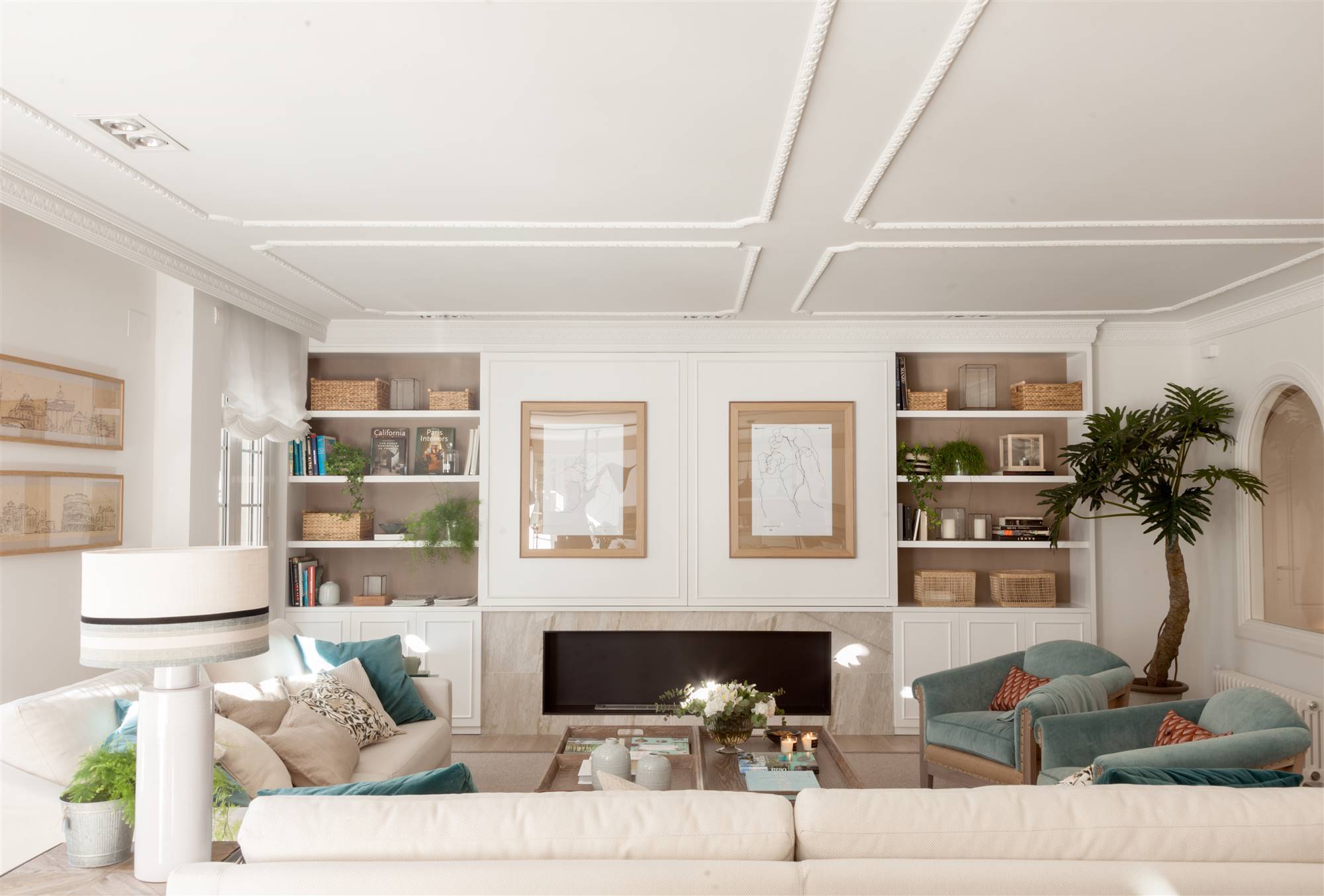 Salón de estilo clásico con molduras blancas, sofás y butacas en azul. 