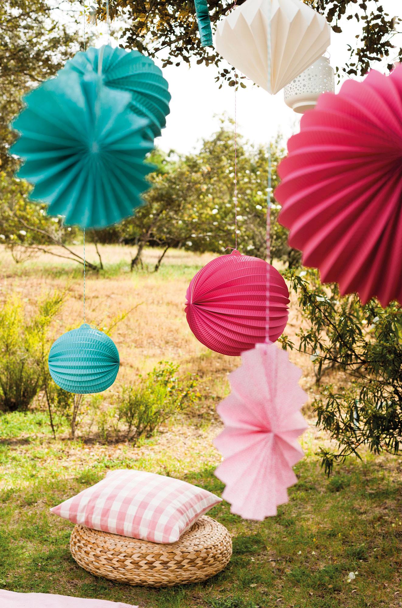 Fiesta en el jardín con adornos de papel en colores rosas y verde agua y un puff de fibras