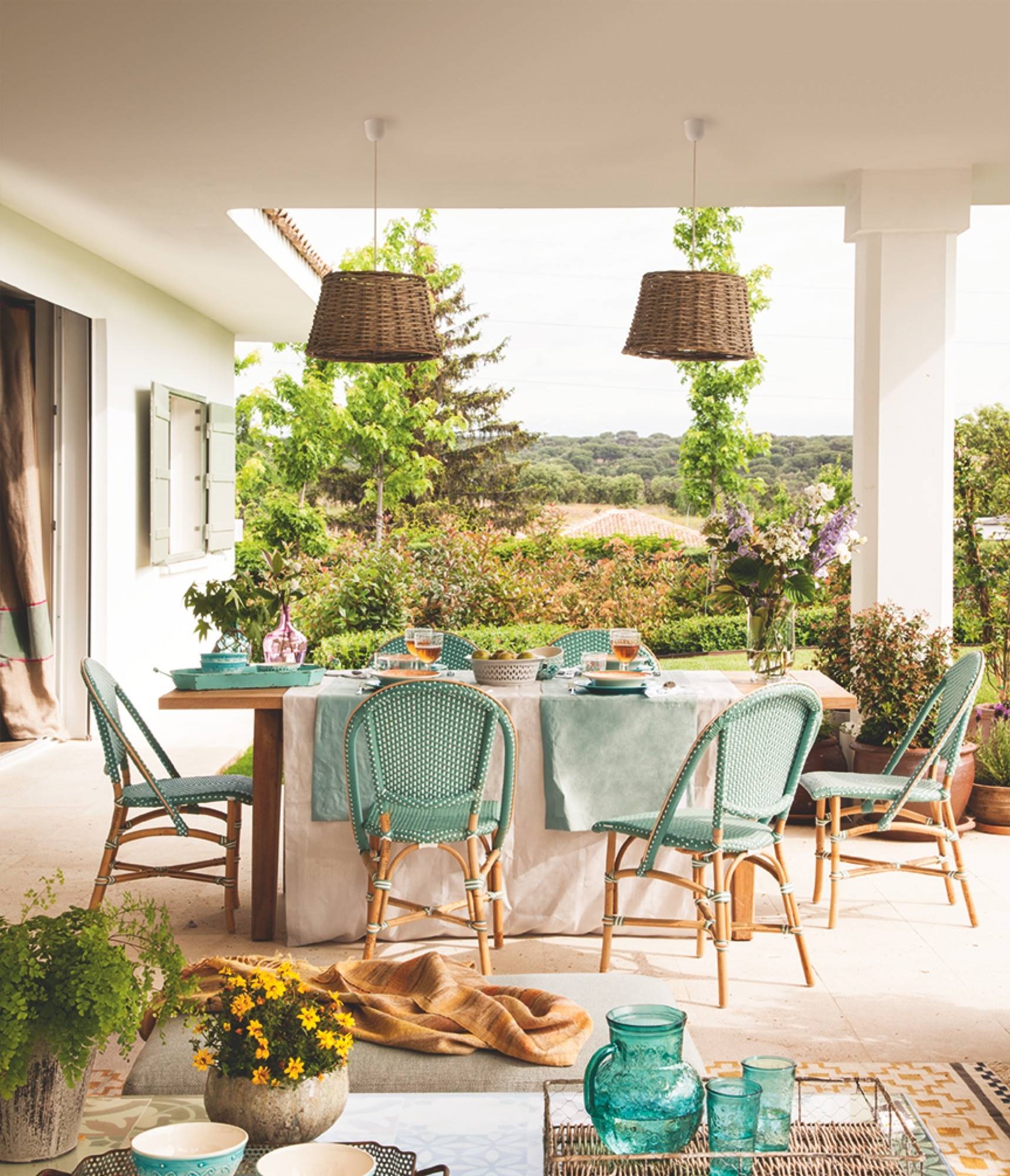 Comedor exterior con salón comedor con sillas tipo bistró en tonos verdes azulados. 