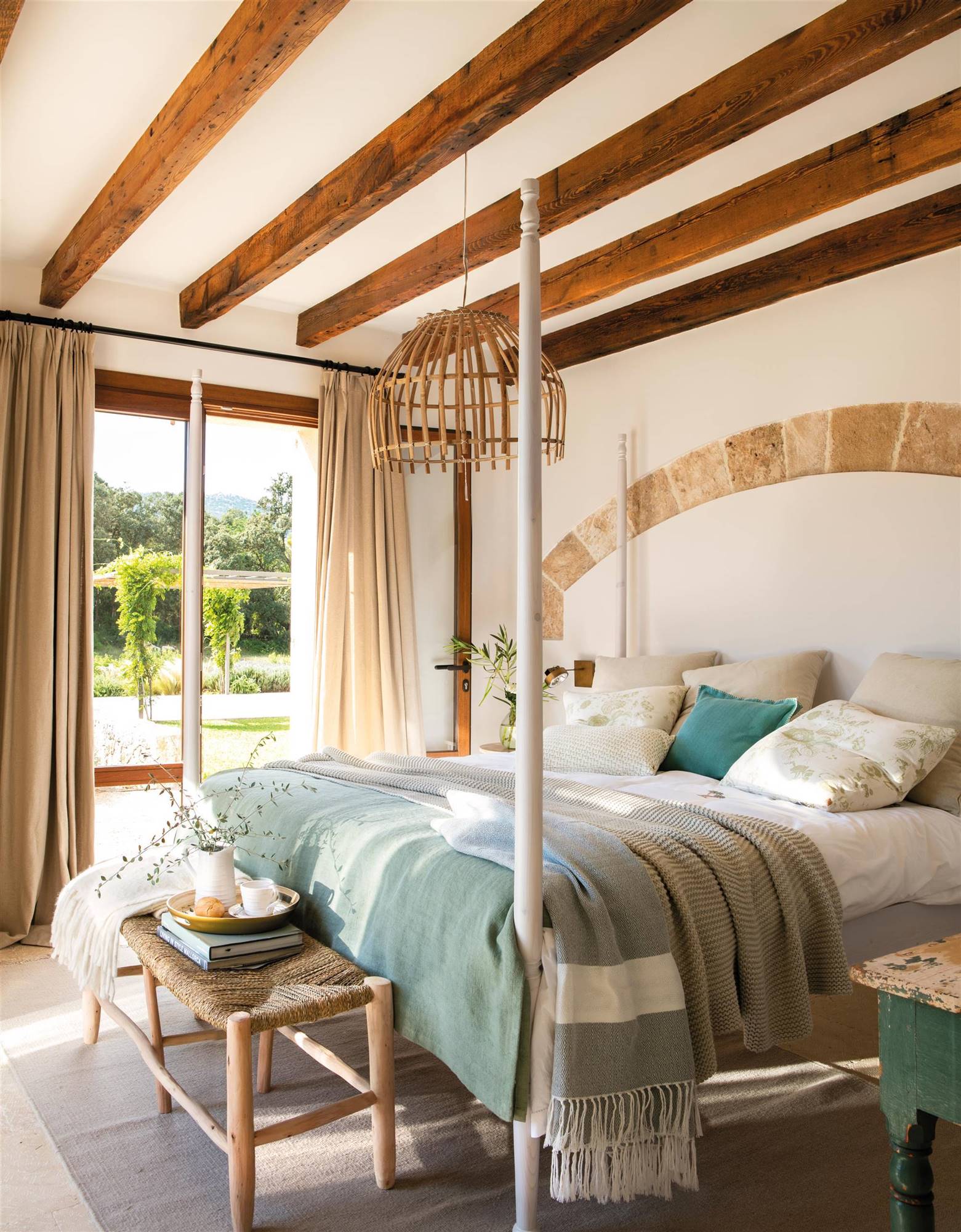 Dormitorio de verano con vigas de madera y revestimiento en arco en zona de cabecero. 