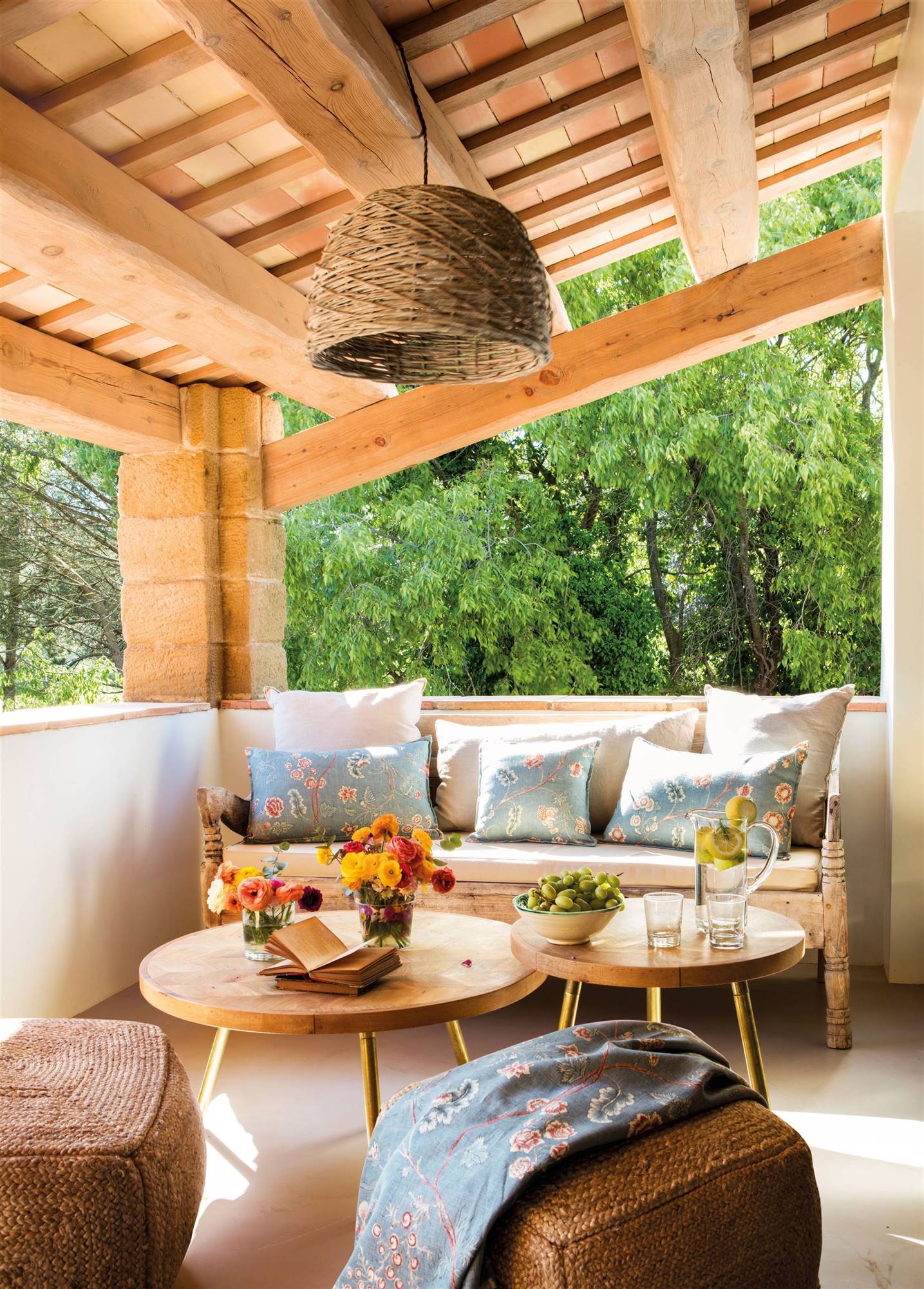 Terraza con un porche con sofá y mesas de madera. 