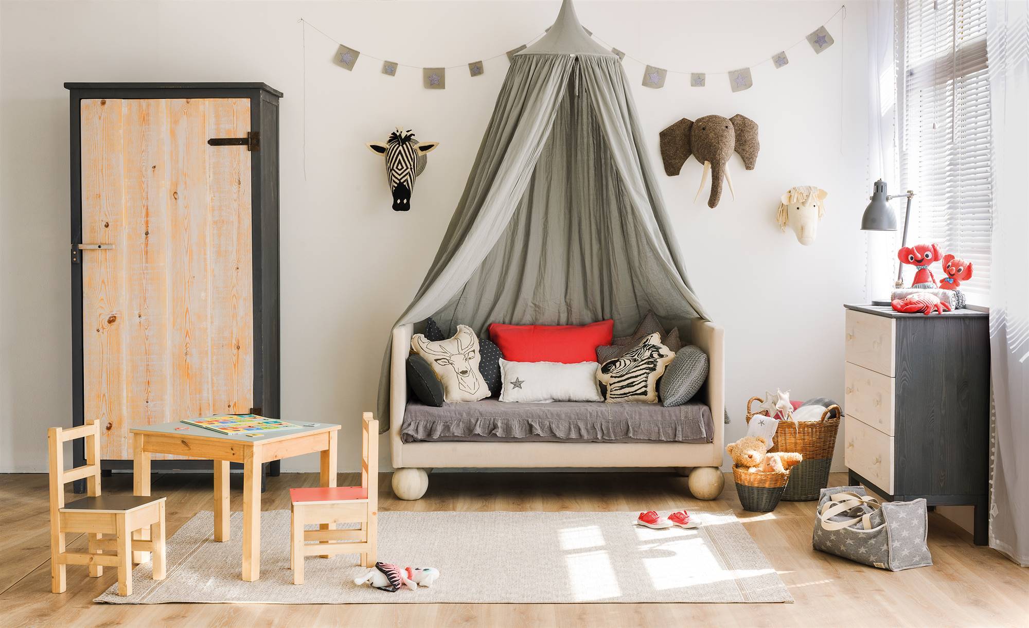 Habitación infantil de estilo nórdico con zona de juegos y cama con dosel gris. 