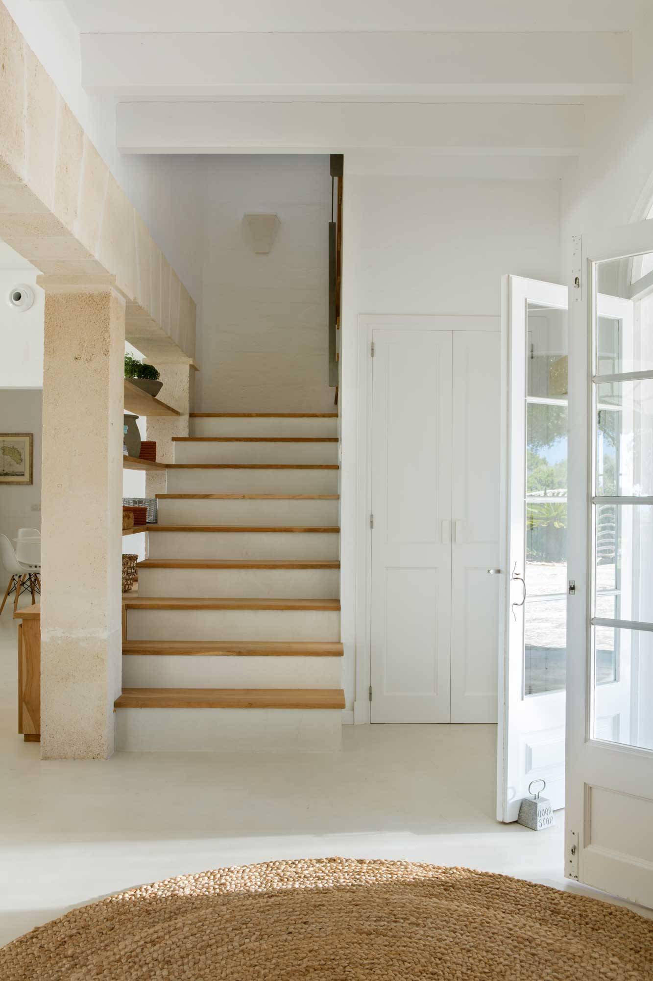 Recibidor blanco de casa de verano con escalera.