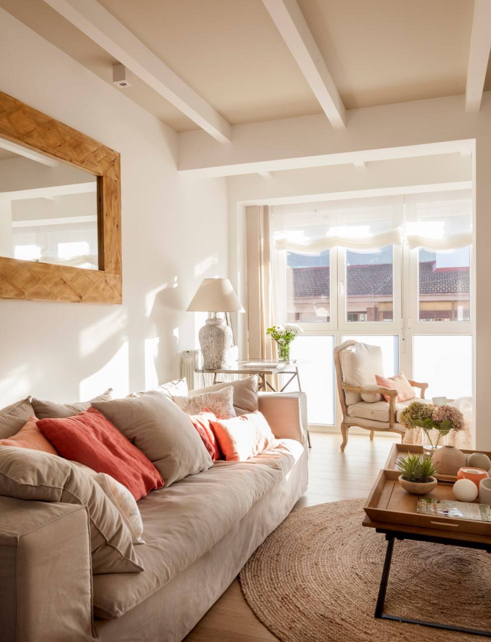 Salón con sofá beige con cojines color coral.  