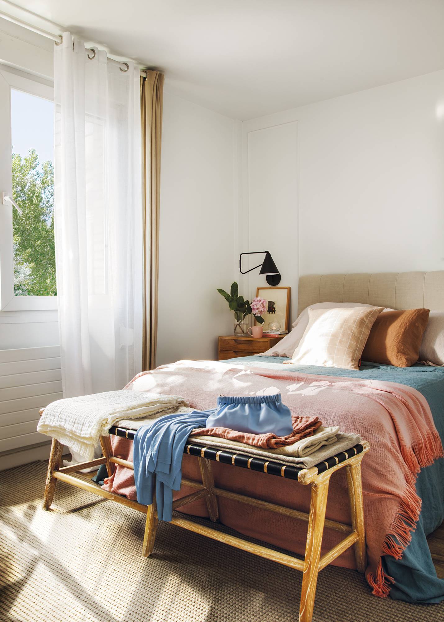 Dormitorio con alfombra marrón y banco de madera al pie de cama. 