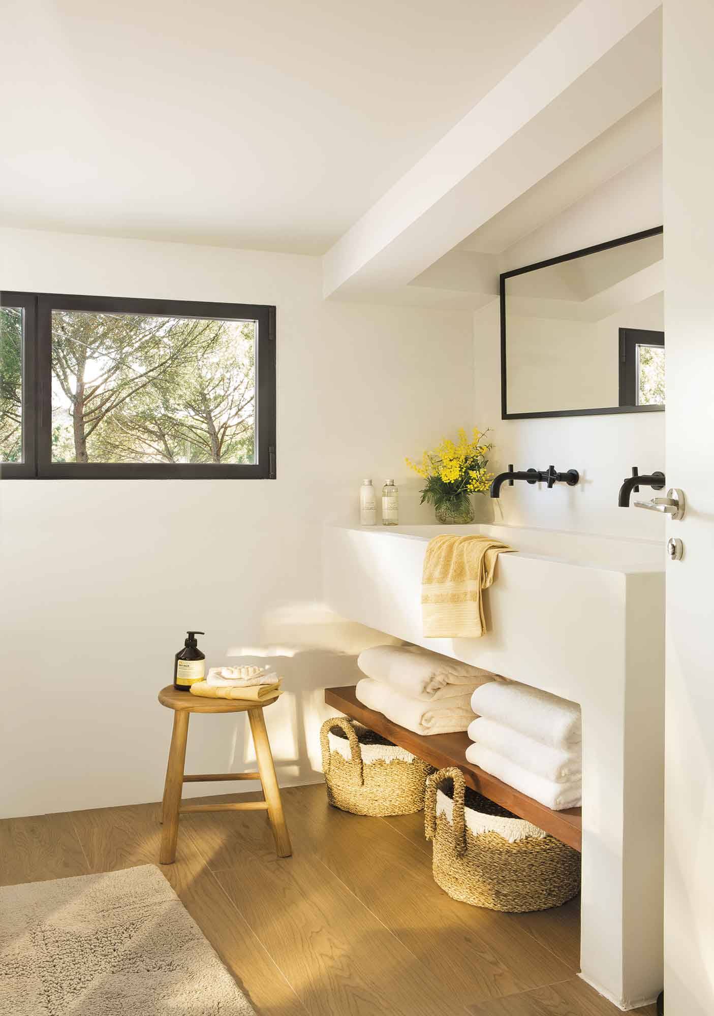 Baño moderno con muebles a medida, estante de madera y grifería y espejo en negro.
