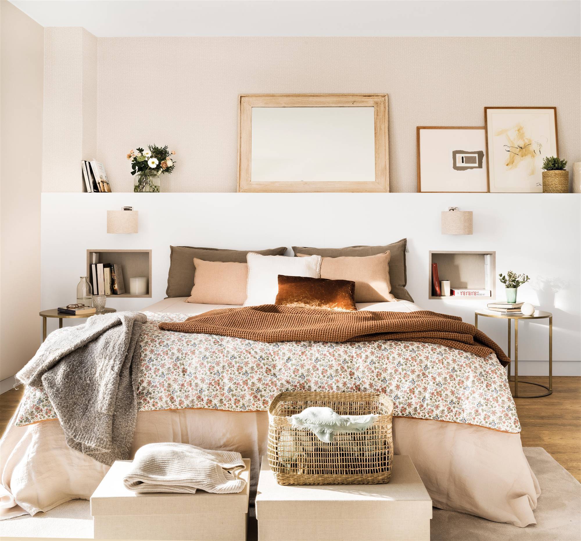 Dormitorio con cabecero de obra en blanco decorado con cuadros y espejos y hornacinas a modo de mesillas de noche integradas.