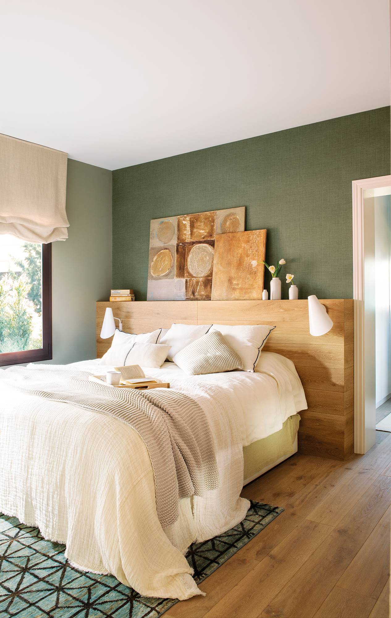 Dormitorio con paredes verde oscuro y cabecero de cama de madera a medida.