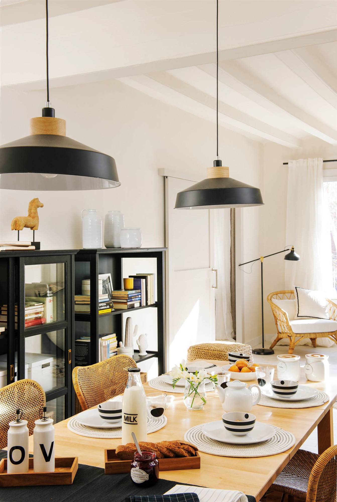 Comedor con mesa extensible, vitrina negra y sillas de mimbre. 