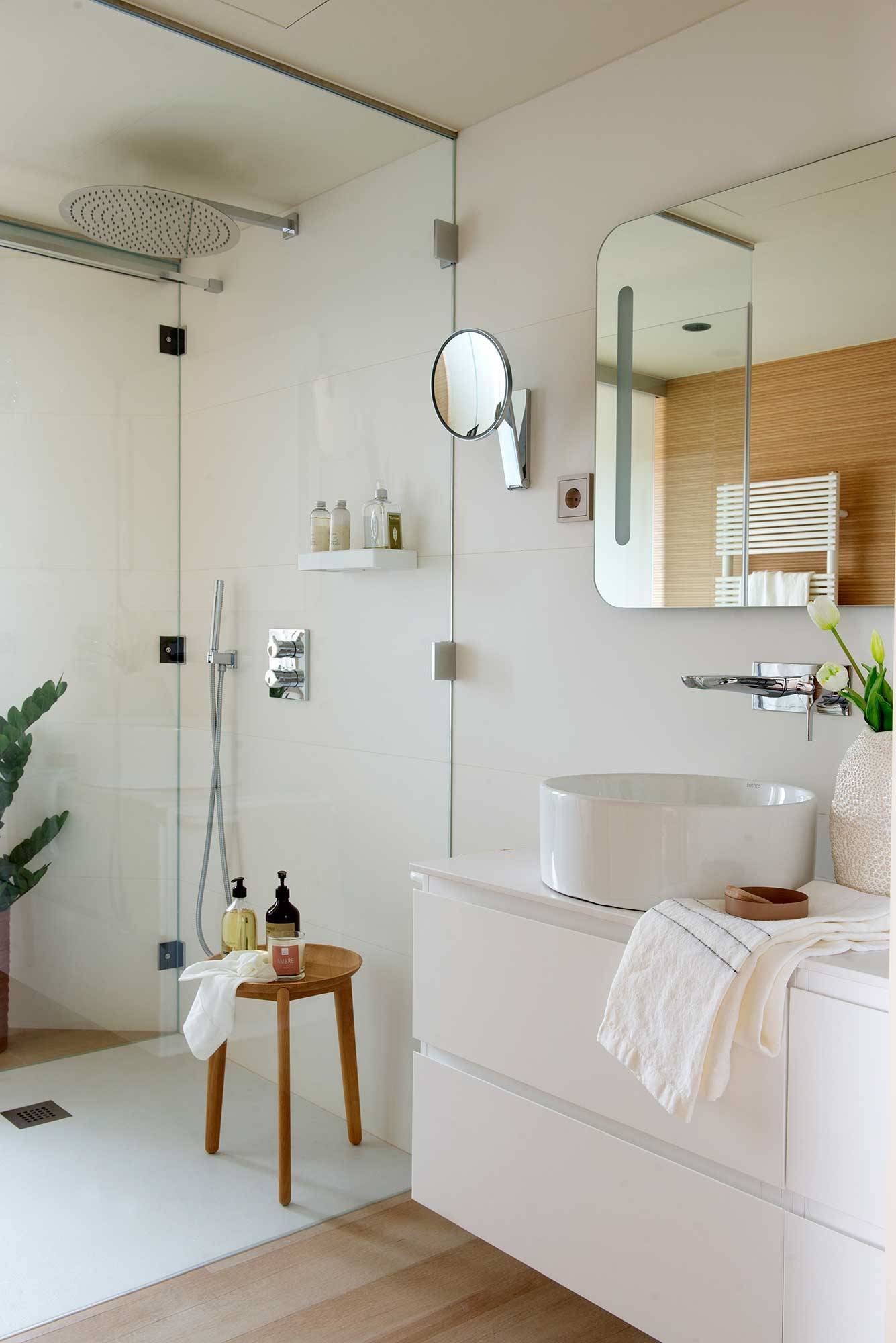 Baño blanco con cabina de ducha transparente.