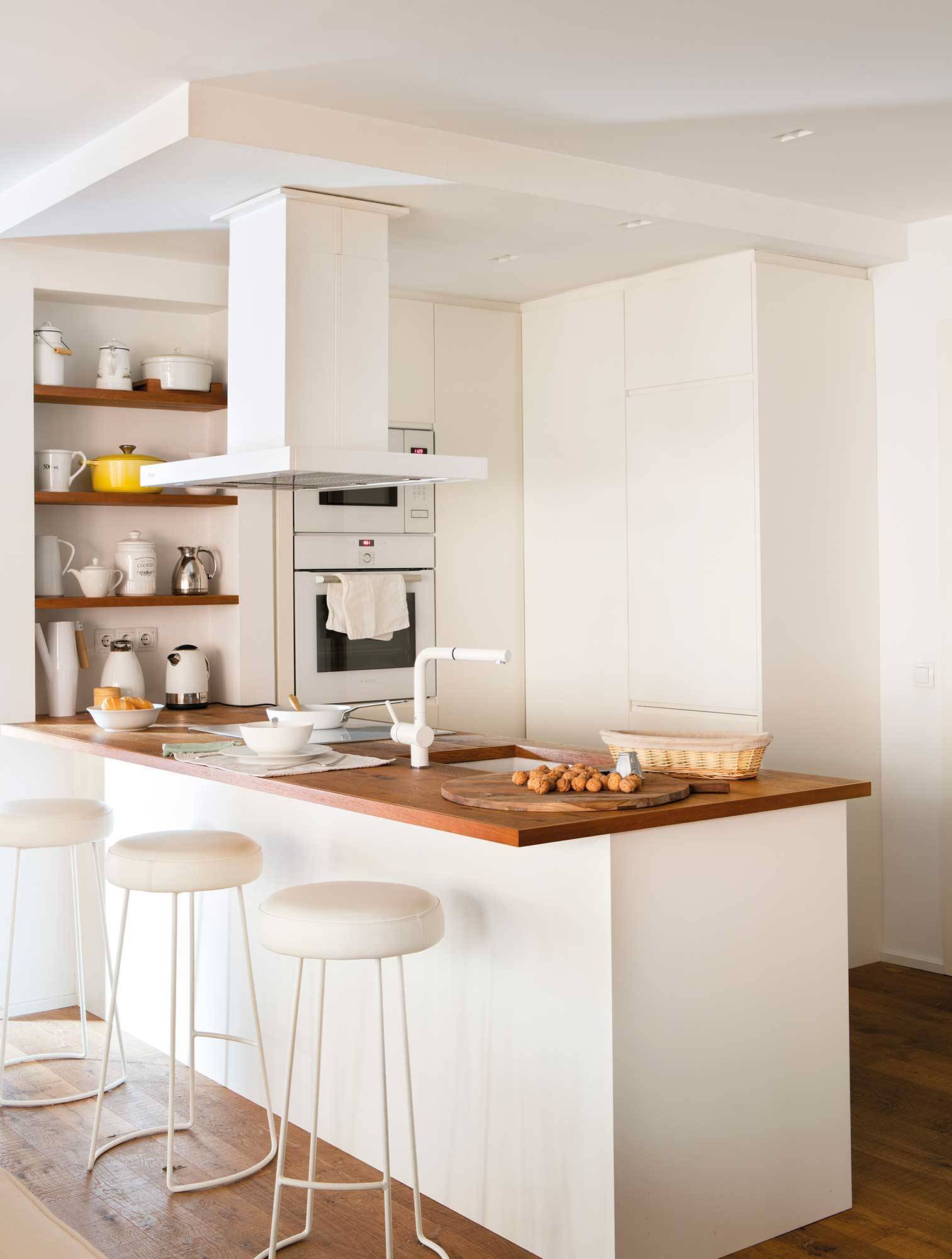 Small, open white kitchen with wooden worktop. 