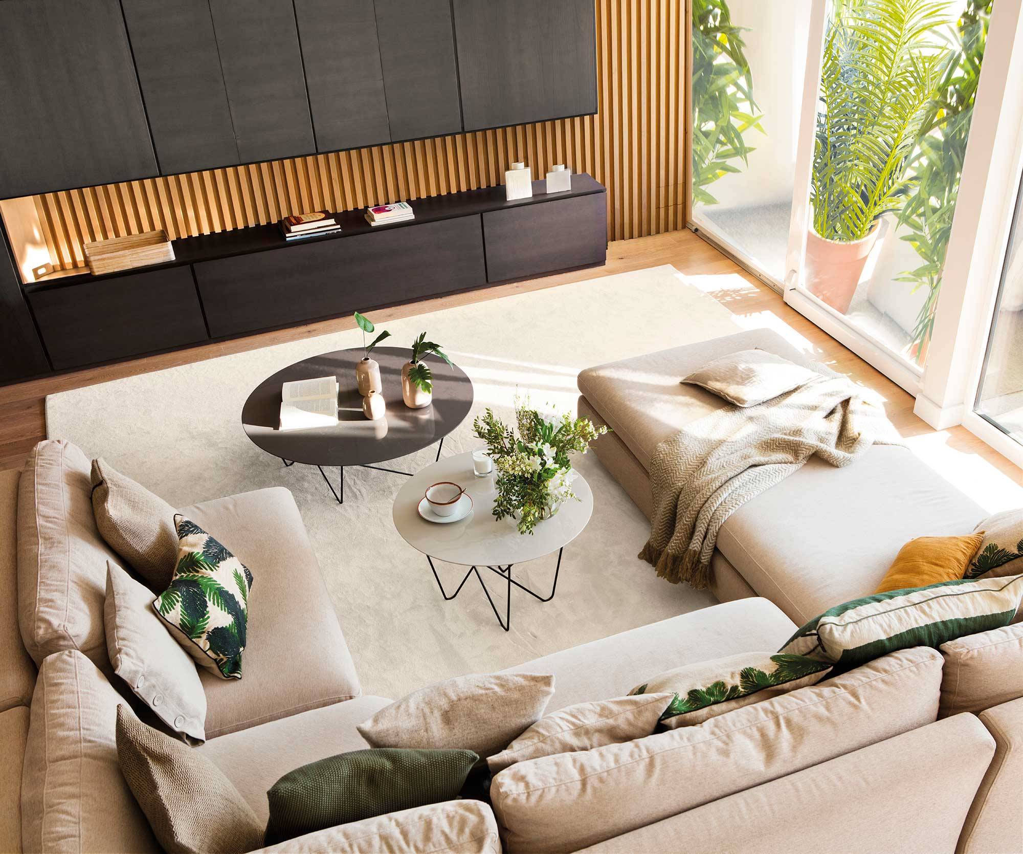 Salón con sofá beige, cojines y alfombra. 