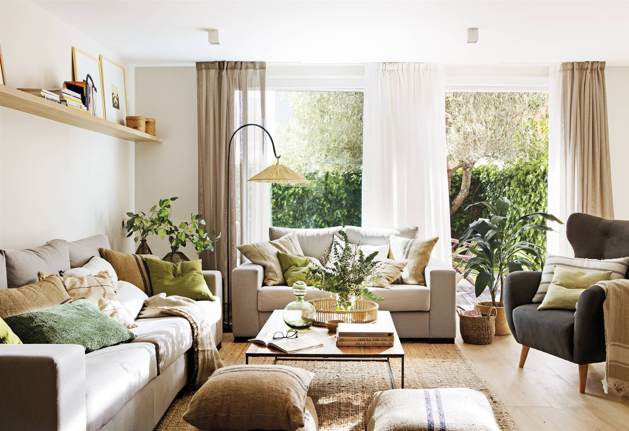 Salón acogedor con sofás grises, cojines verdes, butaca oscura y alfombra de fibras.