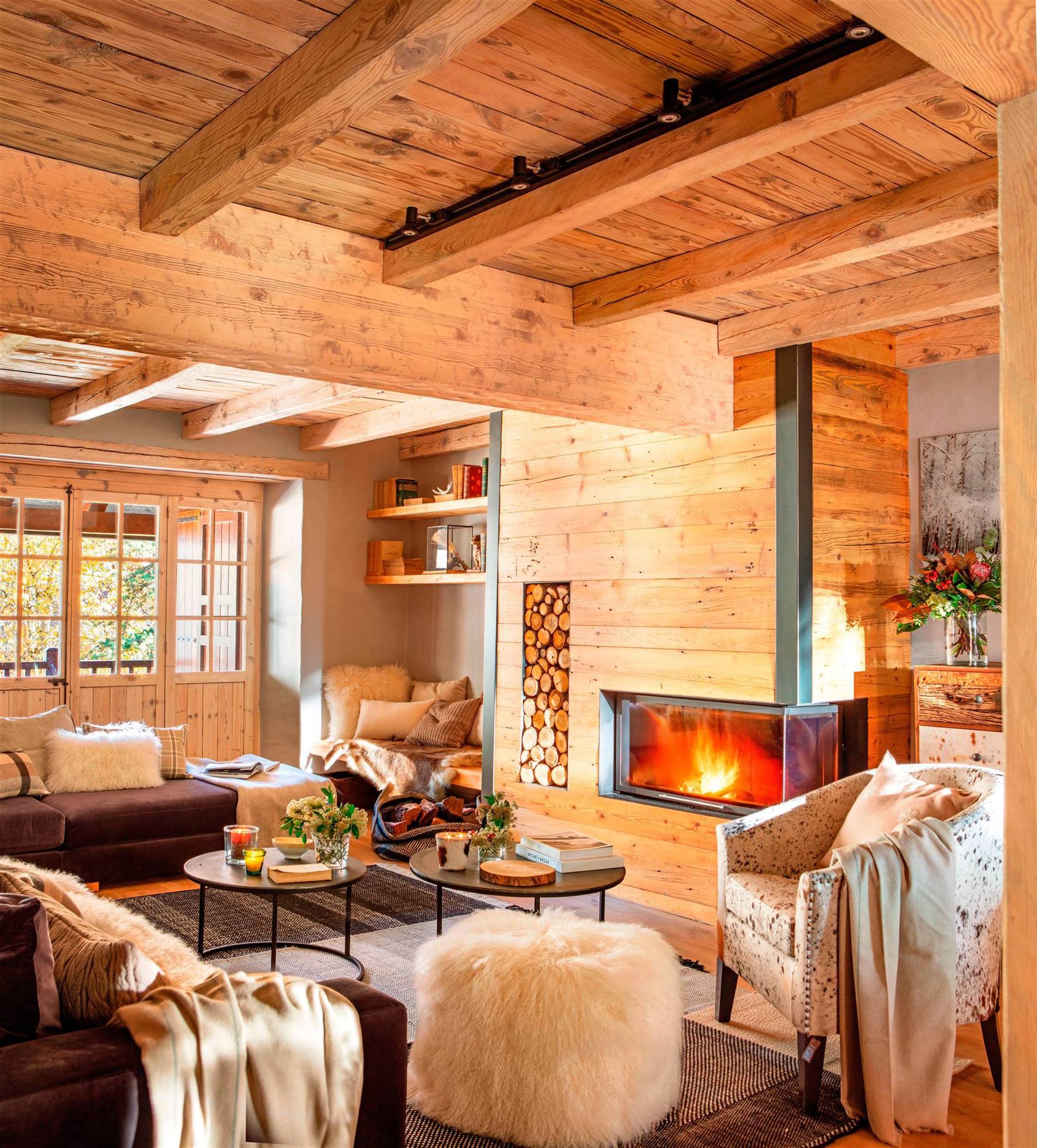 Salón de casa de montaña revestido de madera y con chimenea.