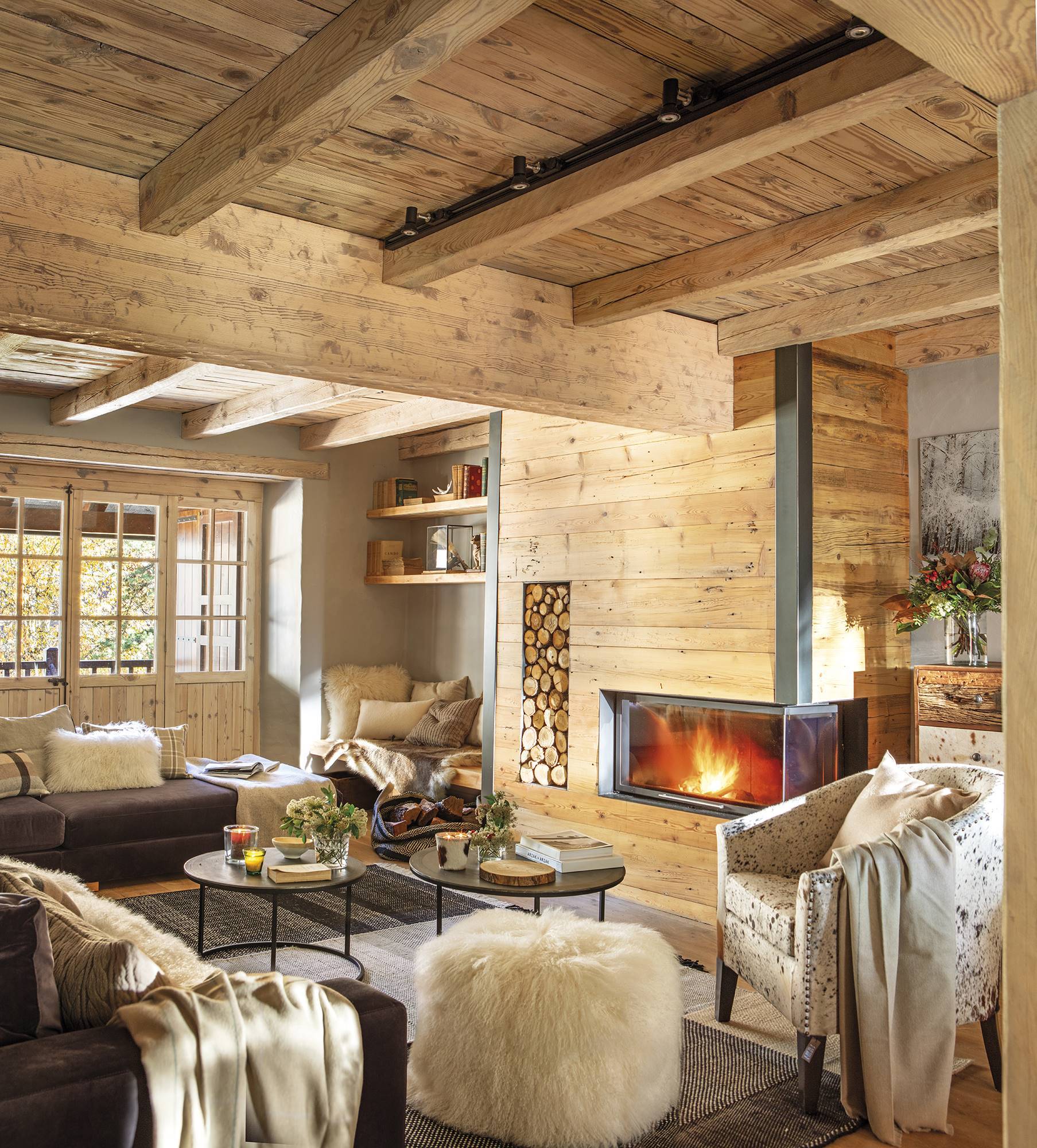 Salón de casa de montaña revestida de madera con chimenea. 