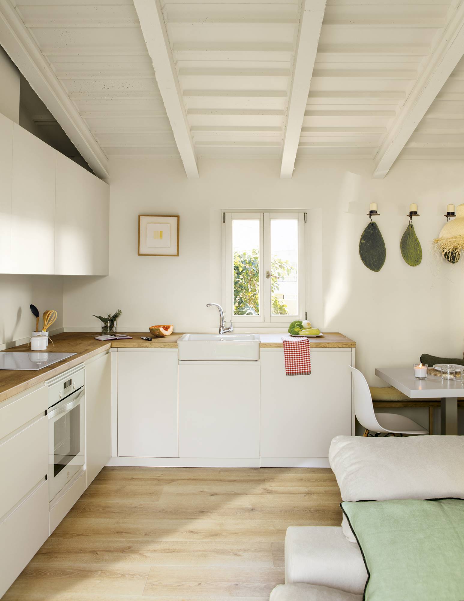 Cocina blanca en L con techo abuhardillado, parquet y office. 