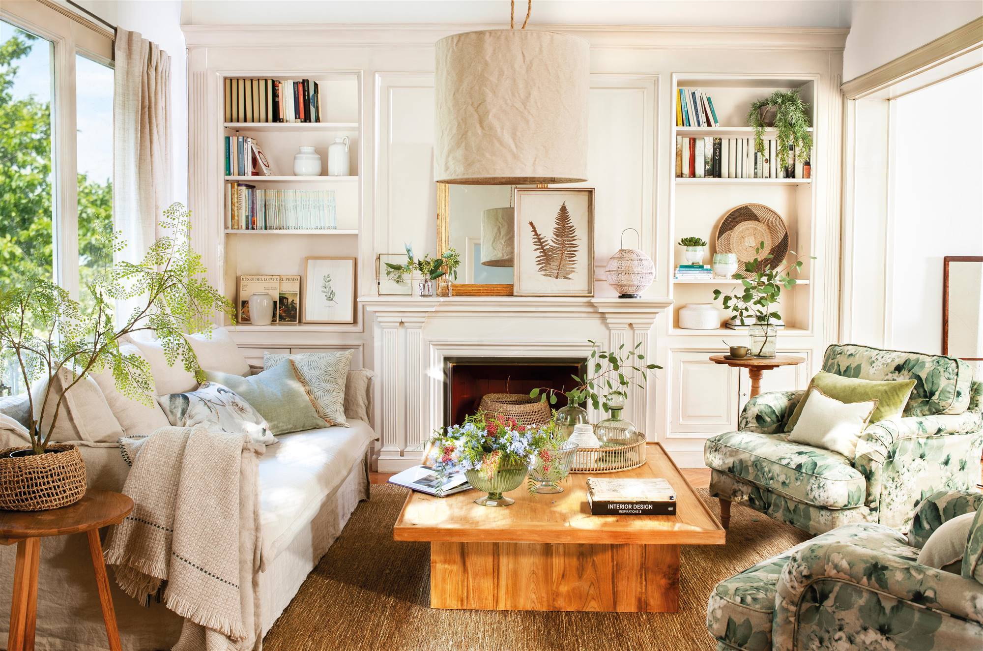 Salón con sofá blanco, chimenea y butacas tapizadas en verde.
