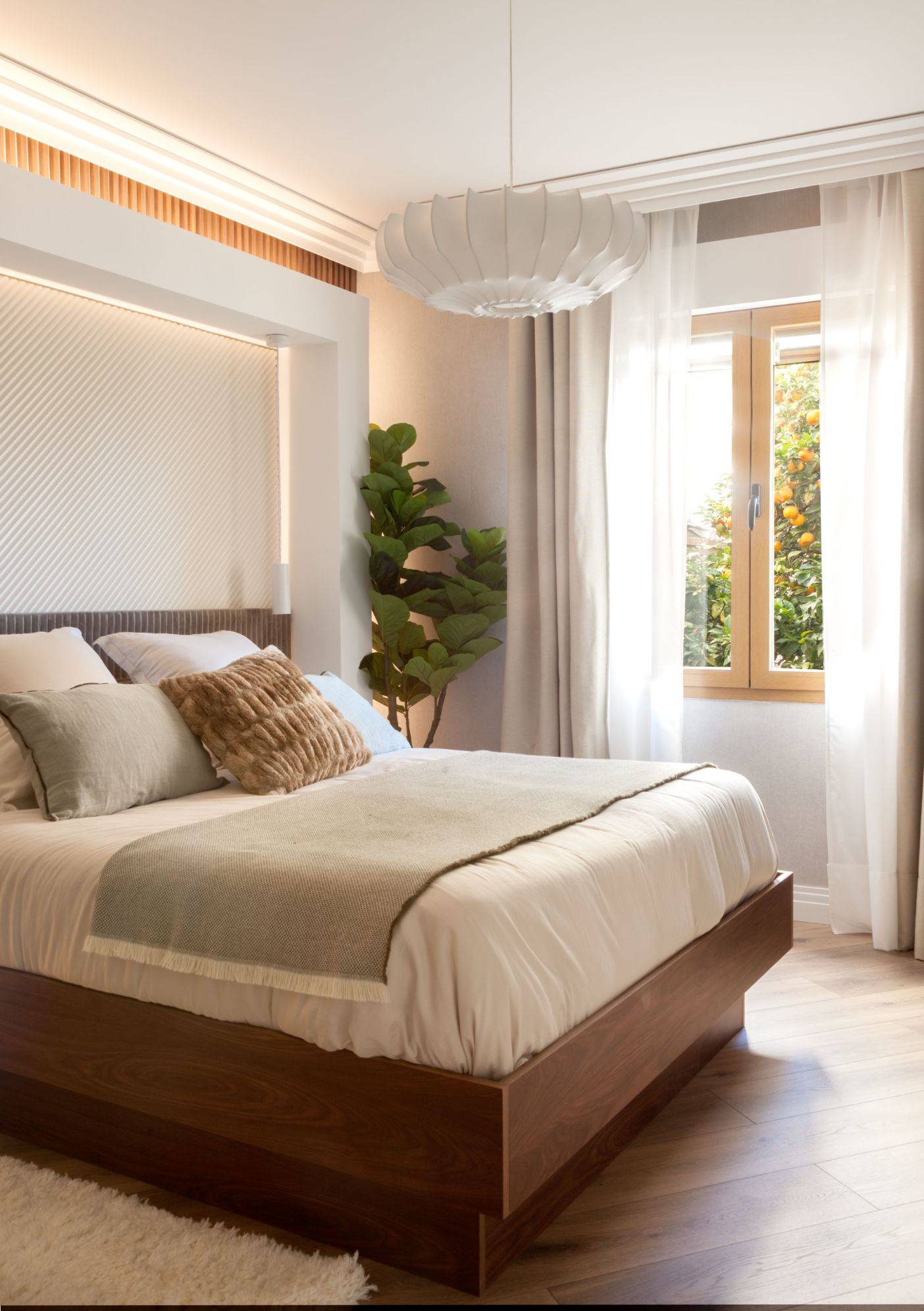 Dormitorio principal elegante con molduras en el techo, cabecero tapizado de terciopelo y cama revestida de madera. 
