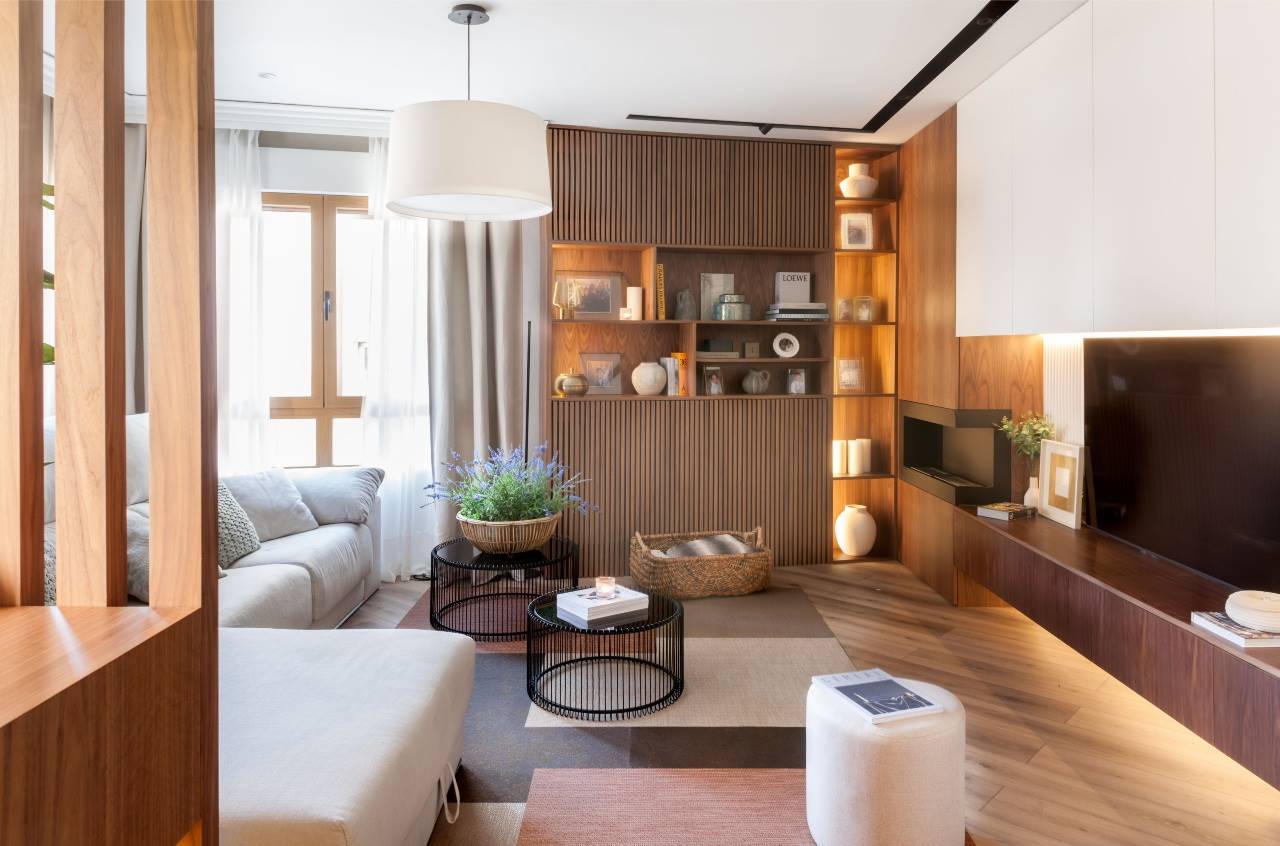 Salón moderno con sofá beige con chaiselonge y puff, alfombra, mesas negras de centro tipo nido y mueble de TV a medida.