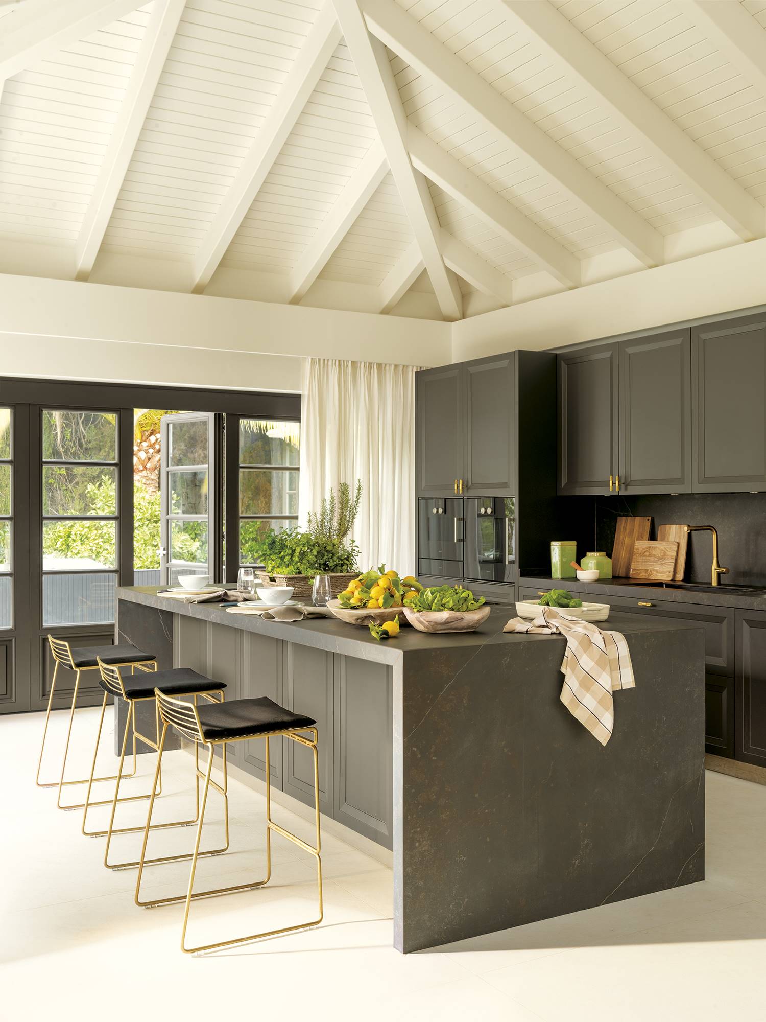 Cocina negra moderna con taburetes dorados y negros. 